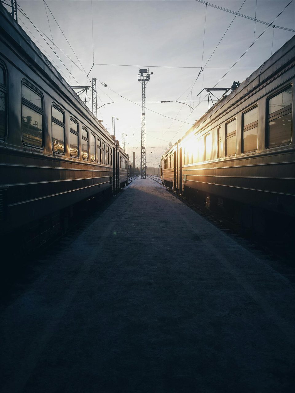 Sunrise between two trains at an empty station, showcasing railway symmetry.. Dmitry Alexandrovich: https://www.pexels.com/@dmitry93
