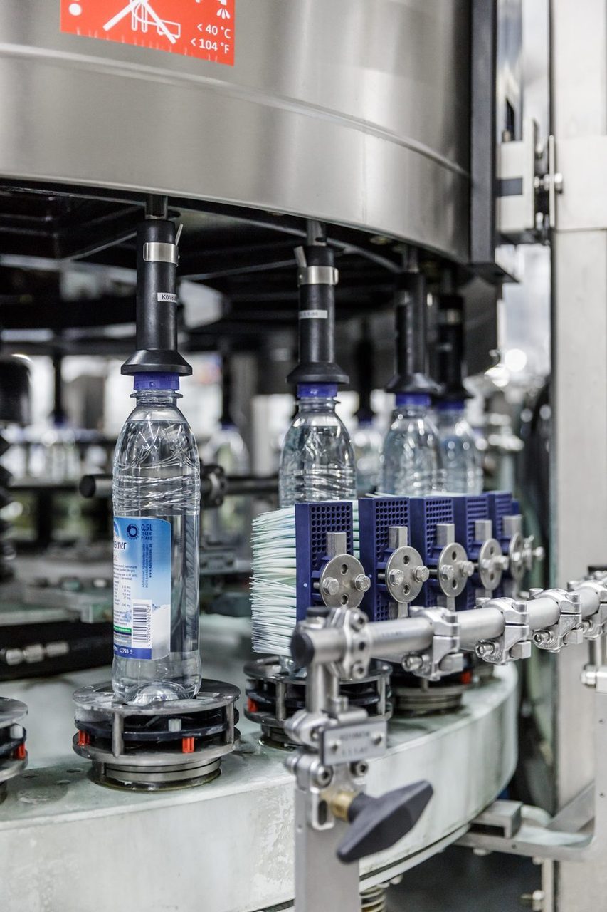 Automated machine filling clear plastic water bottles in a factory.