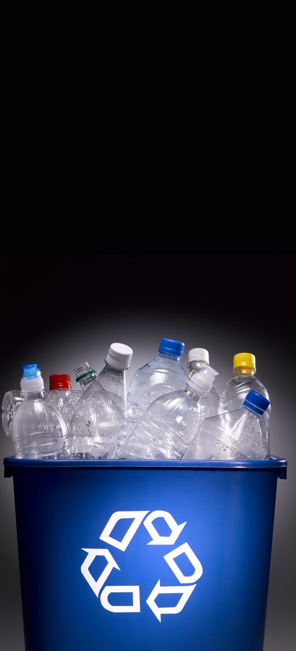 Plastic bottles in trash bin with recycle sign