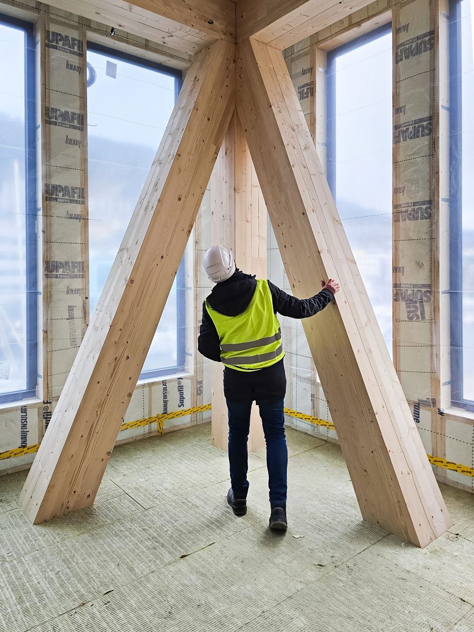 Ny Struktur RIB-ingeniør inspiserer en stor trebjelkekonstruksjon i en bygning under bygging 