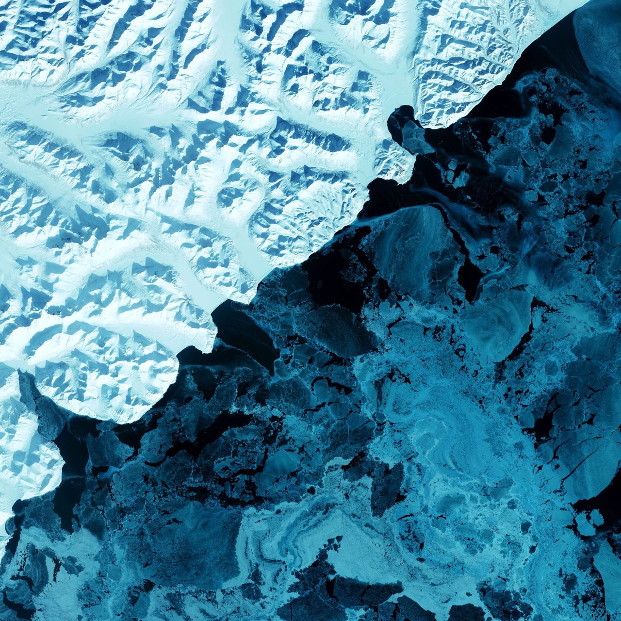 The eastern side of Russia's Kamchatka Peninsula juts into the Pacific Ocean west of Alaska. In this winter image, a volcanic terrain is hidden under snow-covered peaks and valley glaciers feed blue ice into coastal waters.