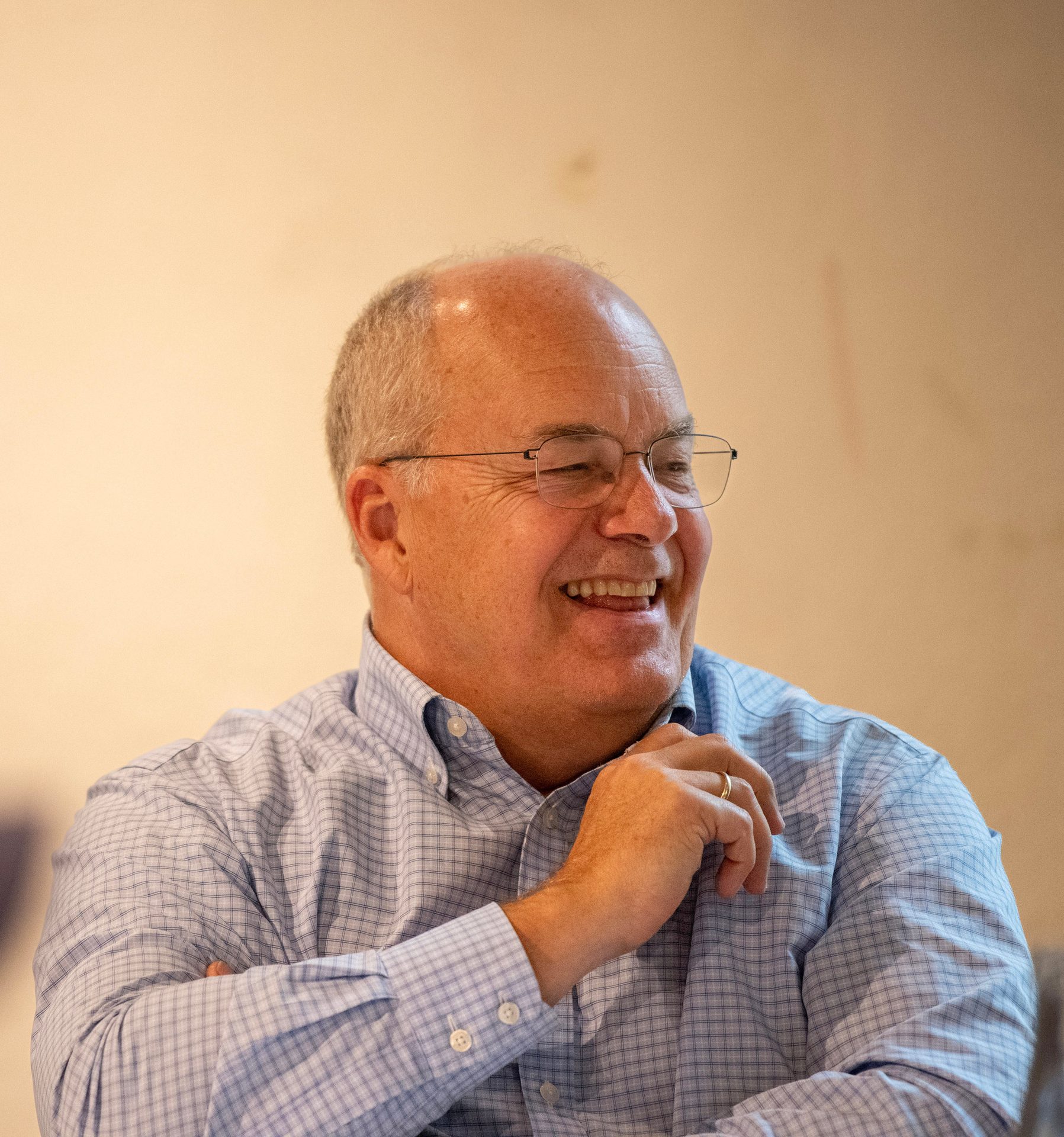 Man in blue plaid shirt and glasses, laughing.