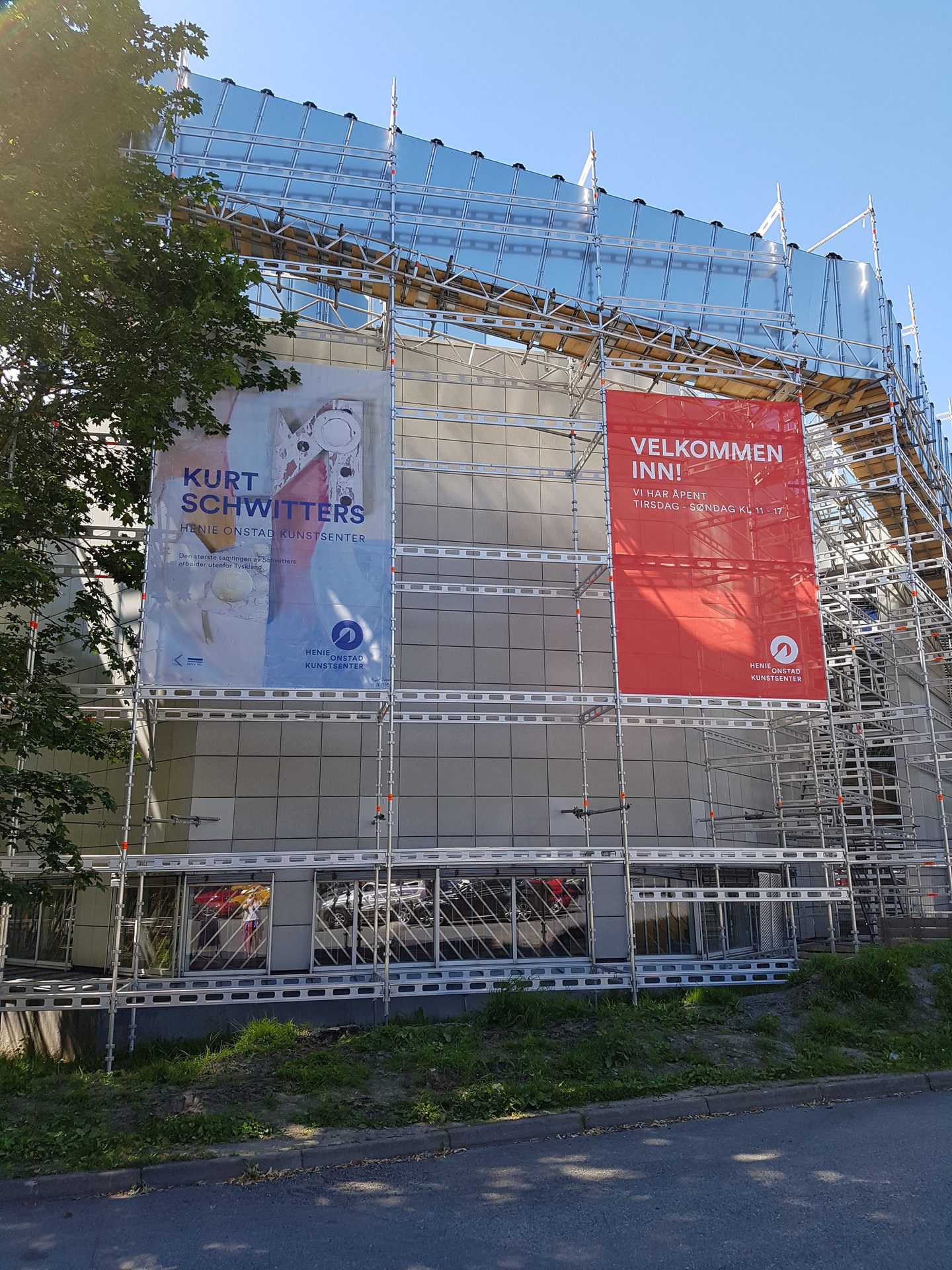 Building with scaffolding and two banners: "Kurt Schwitters" exhibition and "Velkommen Inn!".