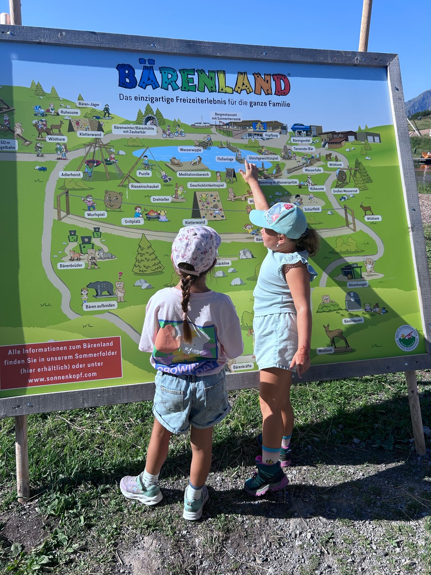 Two young girls intently looking at a large map of Bärenland, with one pointing to an attraction.