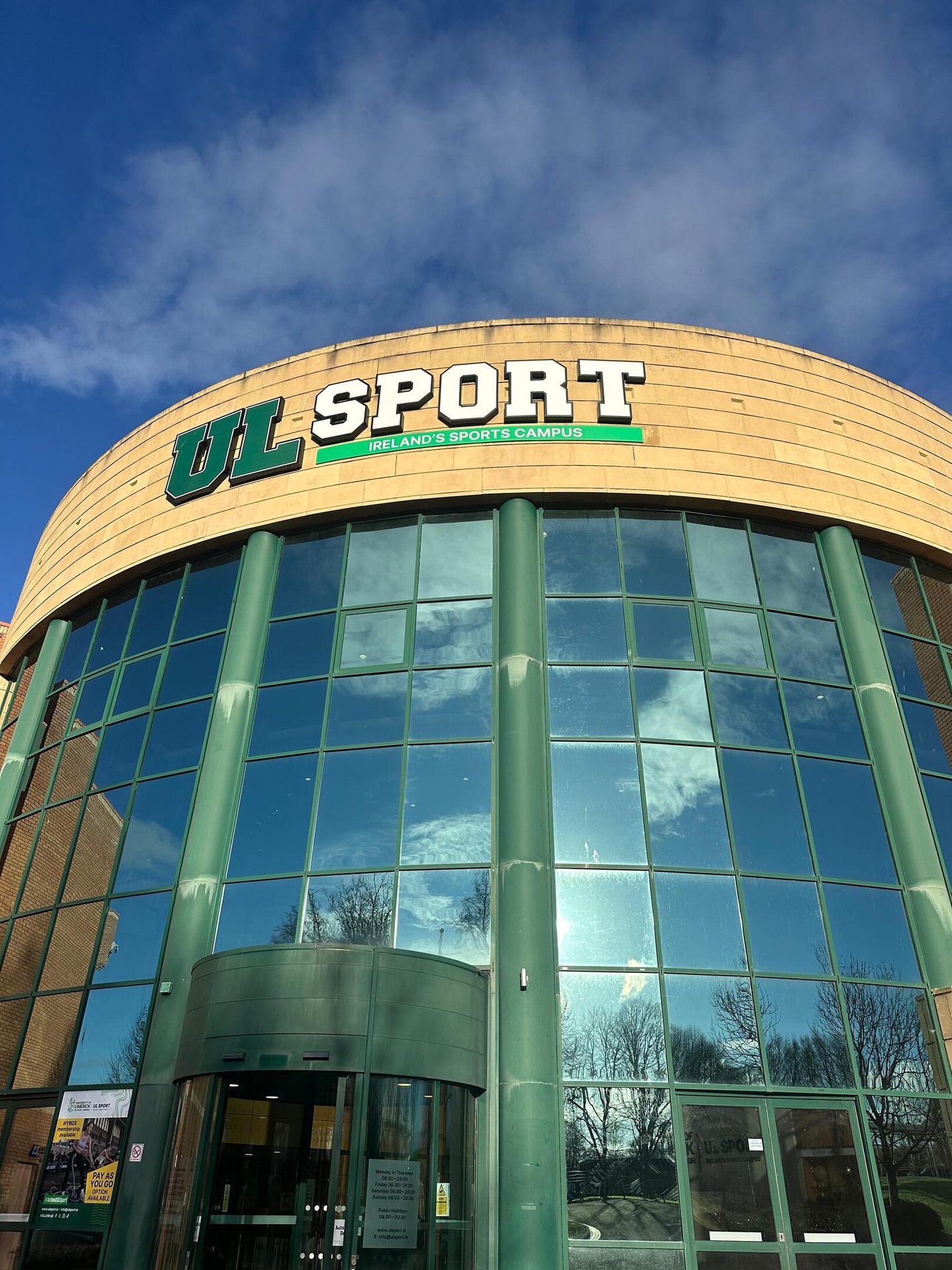 Front view of the UL Sport building, Ireland's Sports Campus, with a glass facade and blue sky.