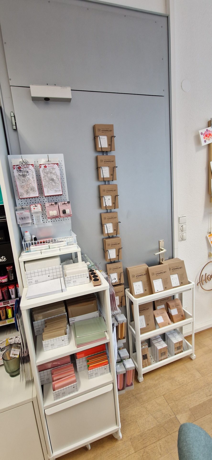 A store display of "Stempelset" stamp kits and paper on white shelves.