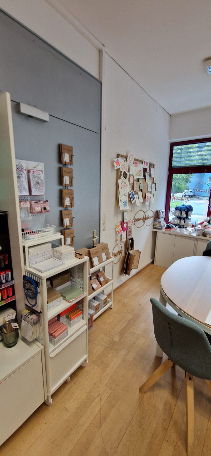 Organized craft room with supplies on shelves, wall art, and a table.