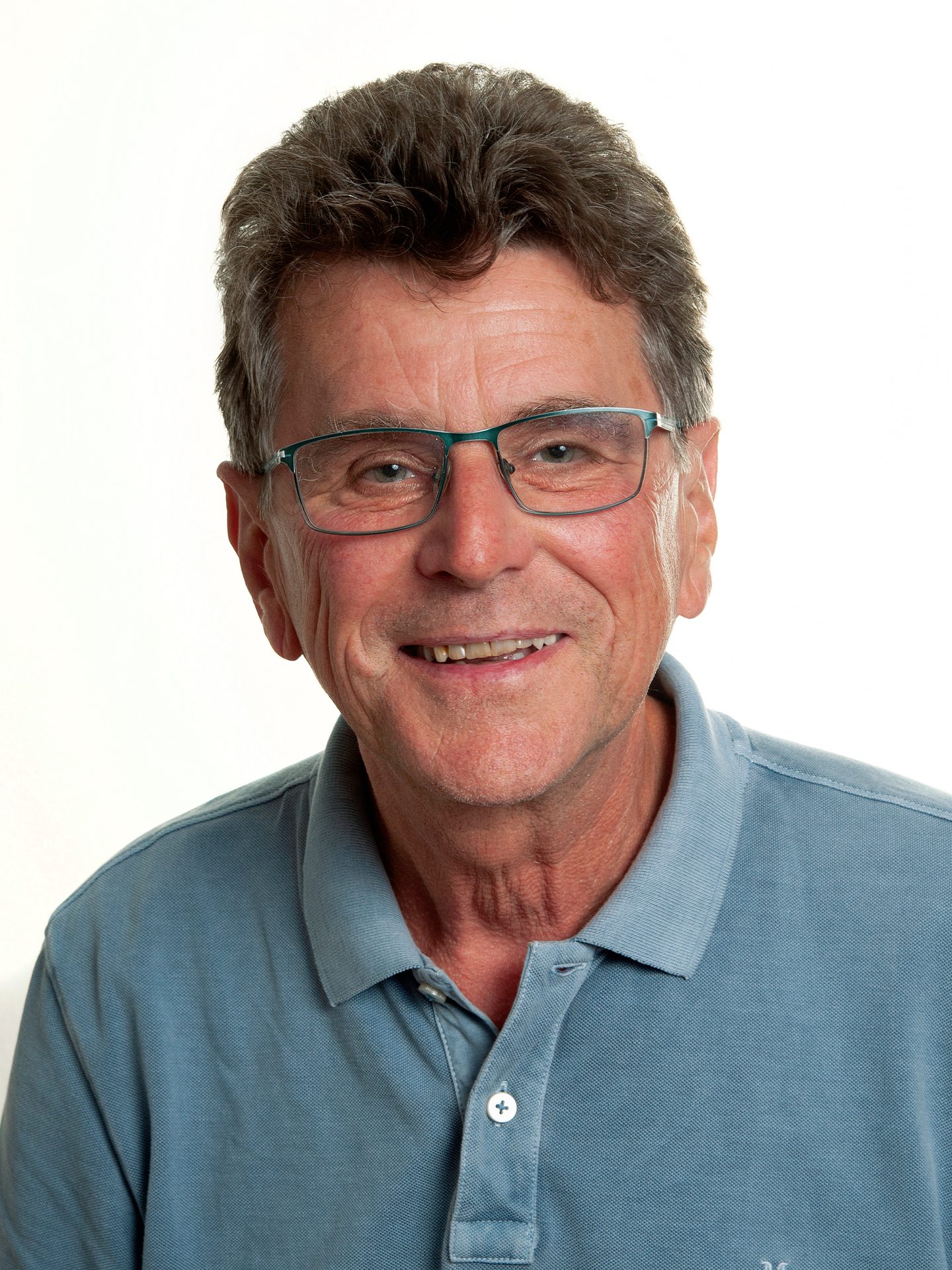 Headshot of a smiling middle-aged man with glasses and a blue polo shirt, looking at the camera.