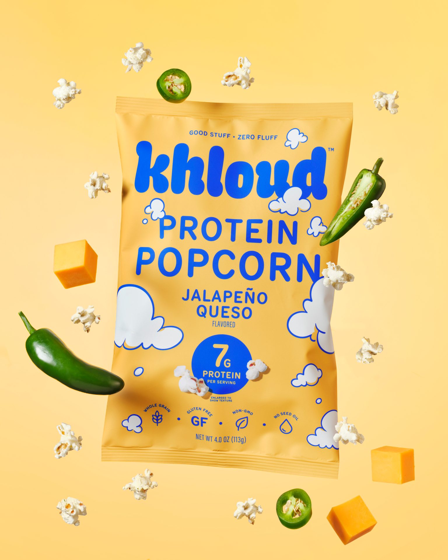 Yellow bag of Khloud Protein Popcorn Jalapeño Queso, surrounded by popcorn, jalapeños, and cheese.