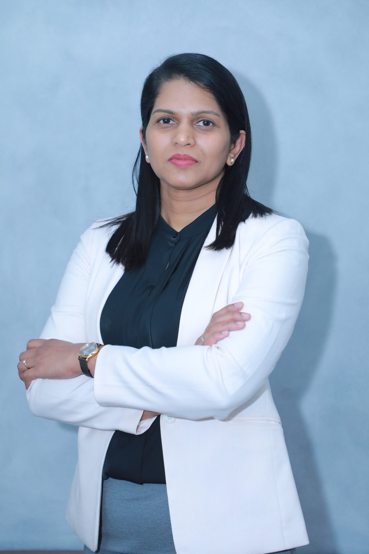 Professional woman in a blazer with crossed arms, looking forward.