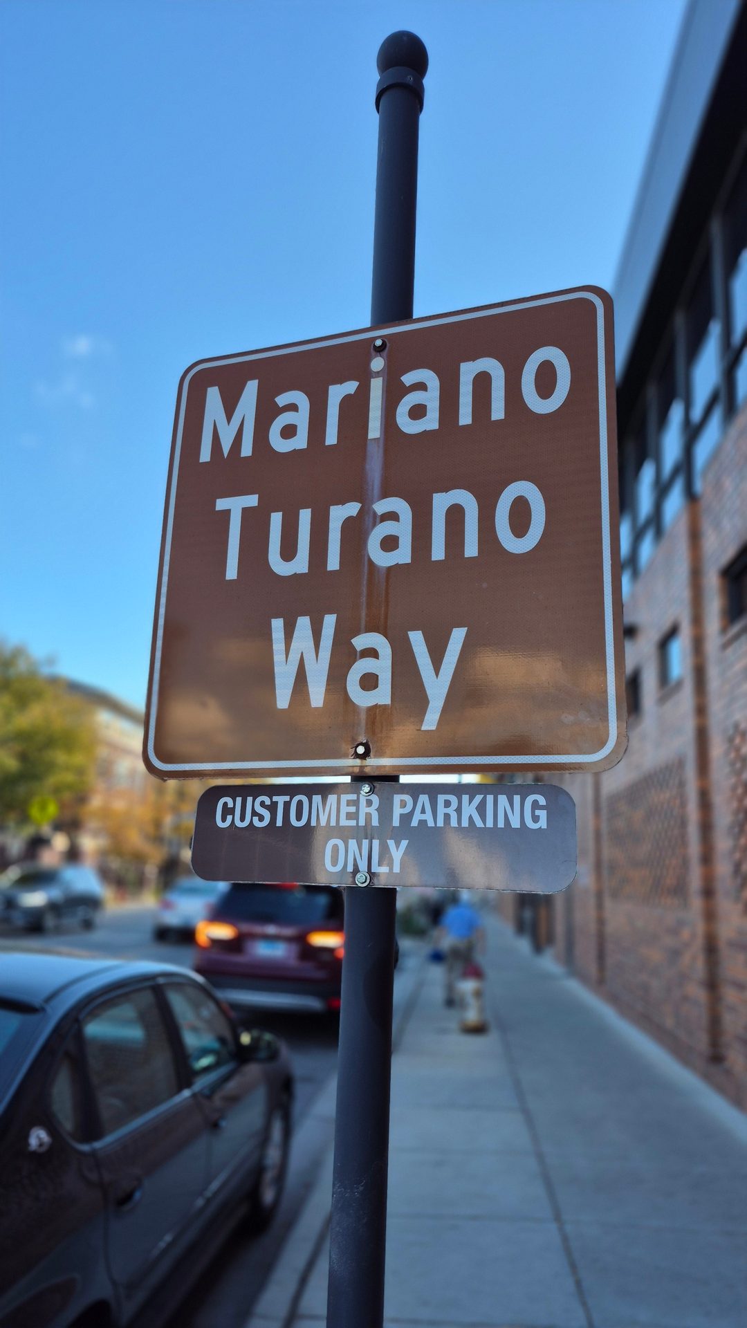 Brown street sign: "Mariano Turano Way", "CUSTOMER PARKING ONLY".