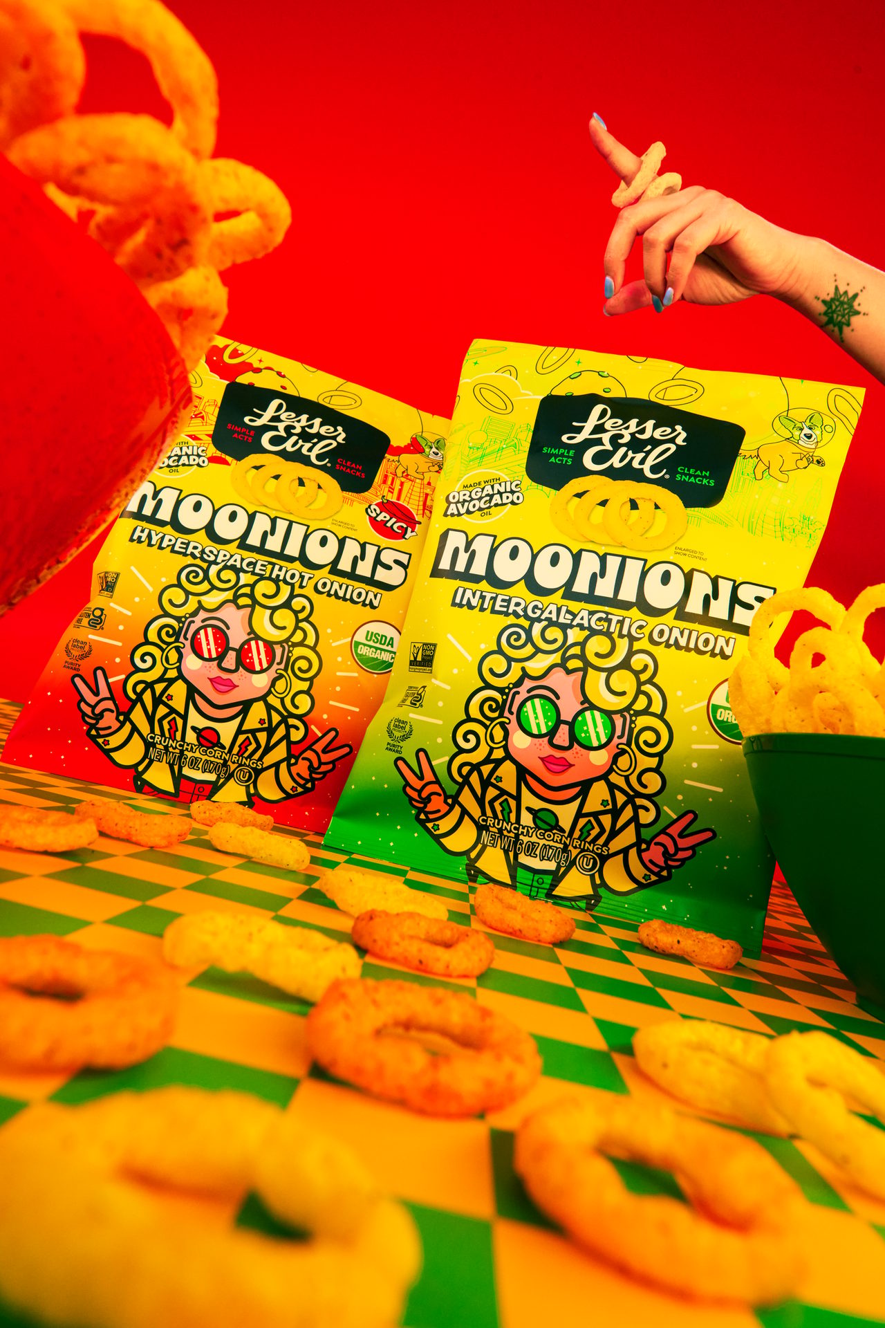 Two bags of LesserEvil Moonions, Hyperspace Hot Onion and Intergalactic Onion, with a hand holding a ring.