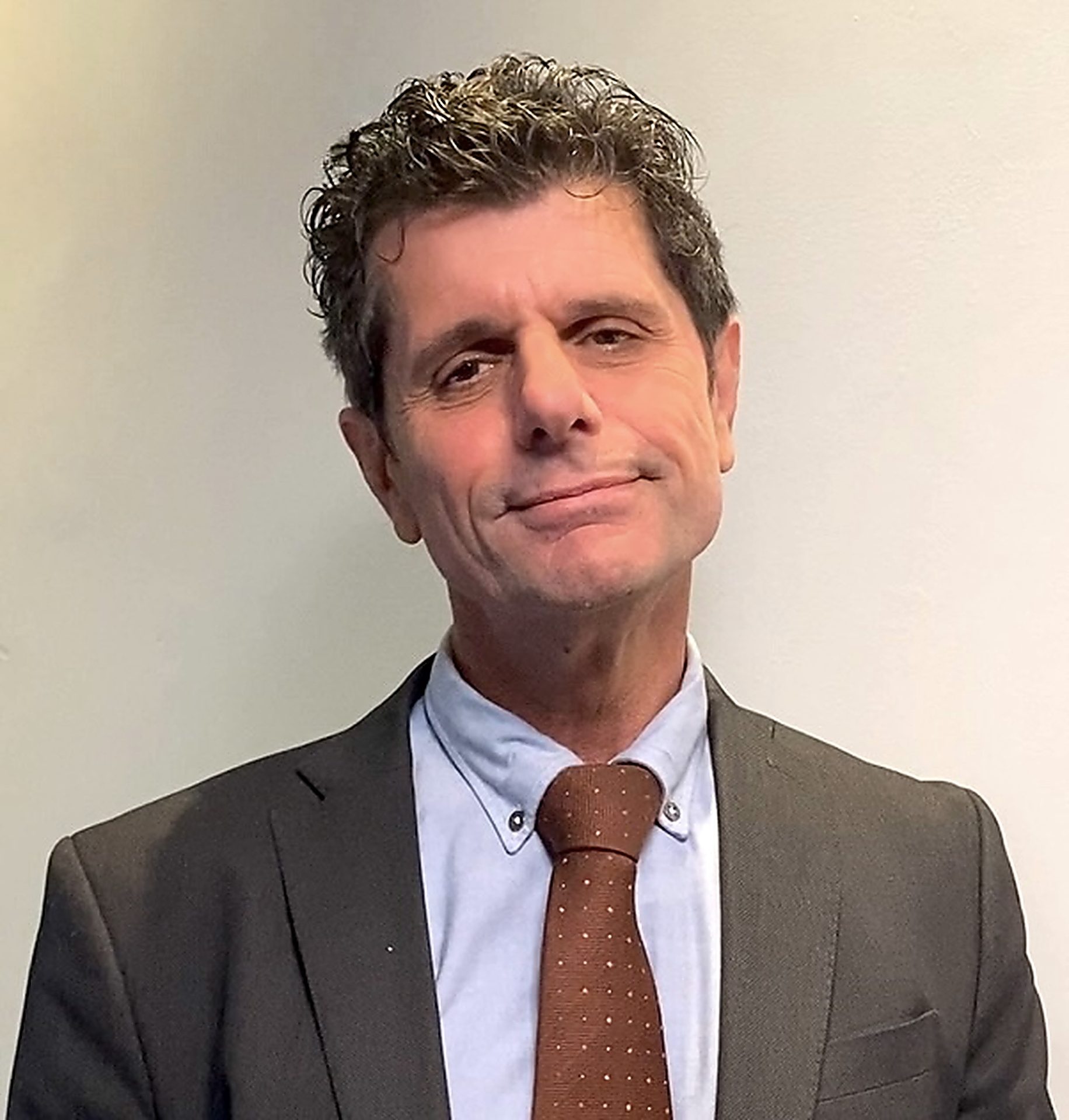 Man in a suit and tie, smiling at the camera.