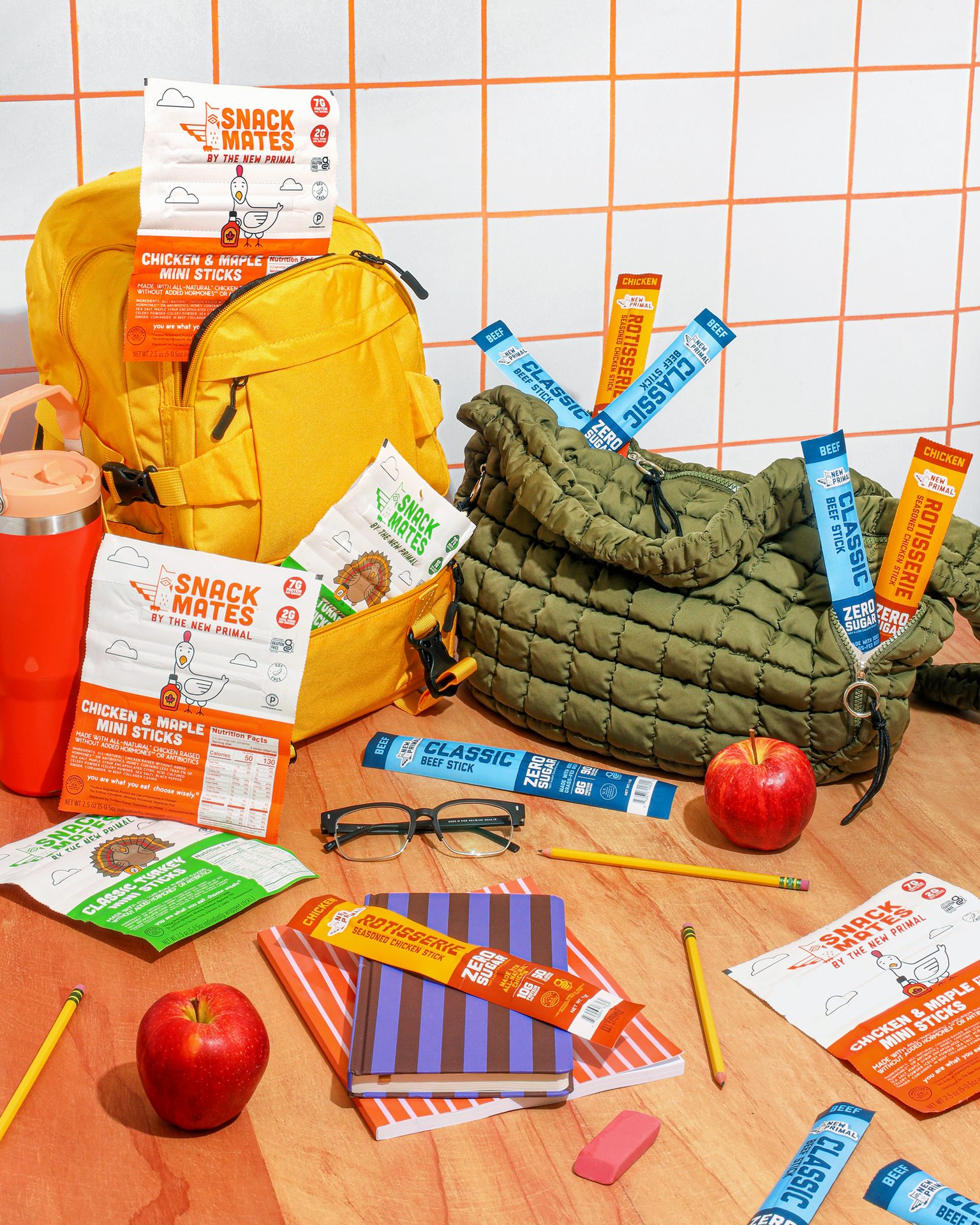Back-to-school essentials including backpacks, various snack sticks and pouches, apples, and school supplies.