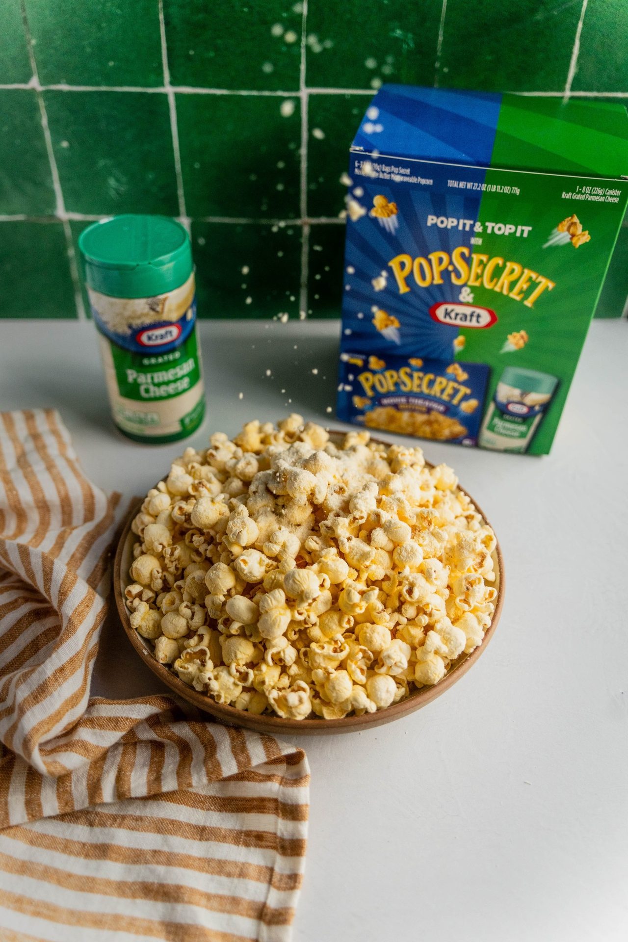 Popcorn topped with grated Parmesan, alongside Kraft Parmesan and Pop Secret box.