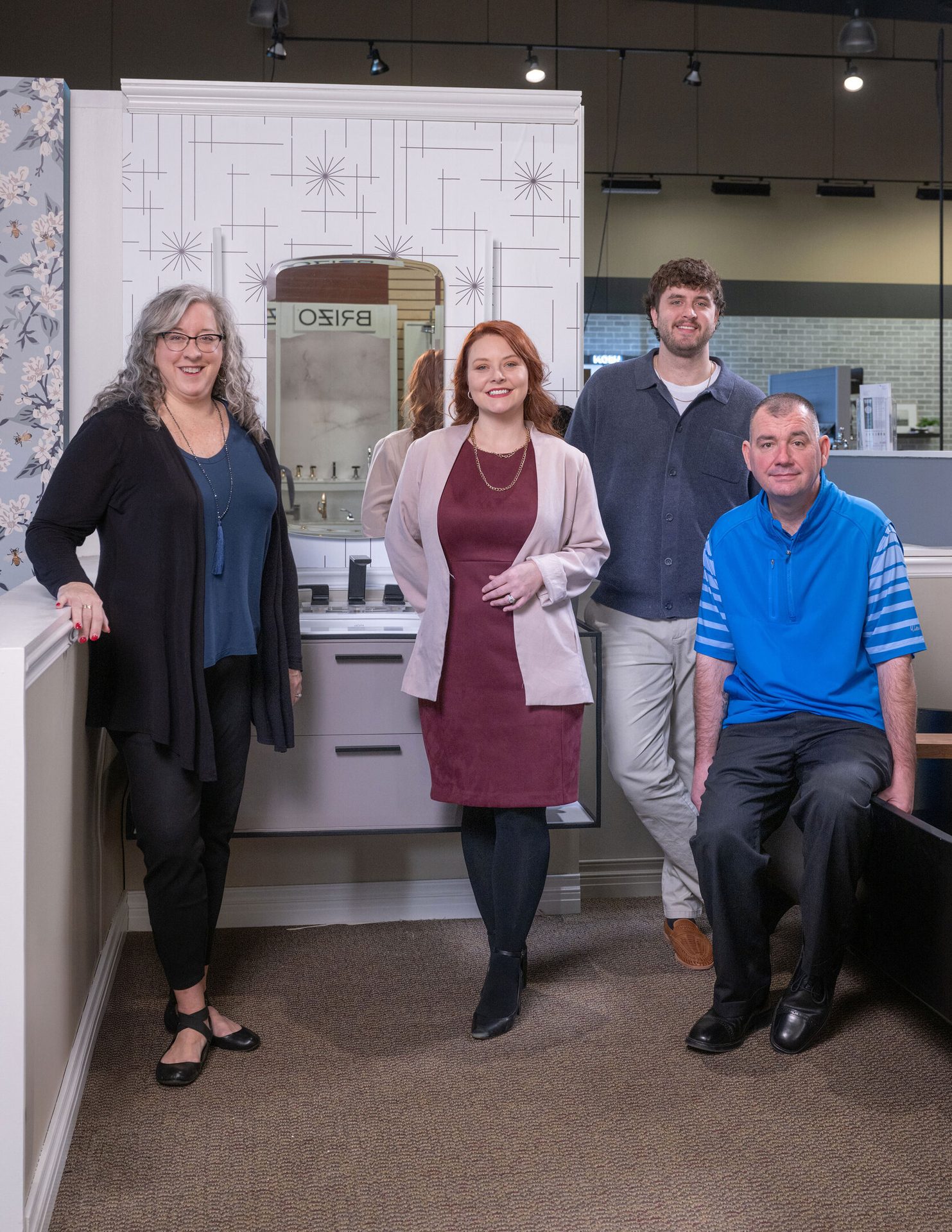 Four diverse individuals—two women and two men—pose in a showroom, smiling.