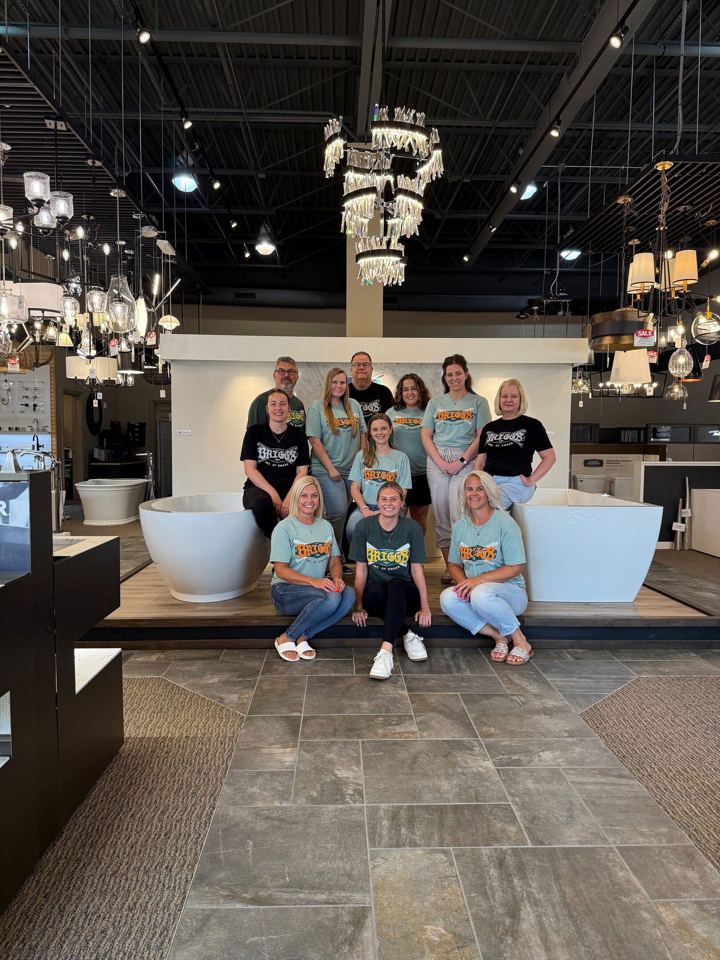 Briggs Inc. of Omaha team poses in their showroom with bathtubs and lights.
