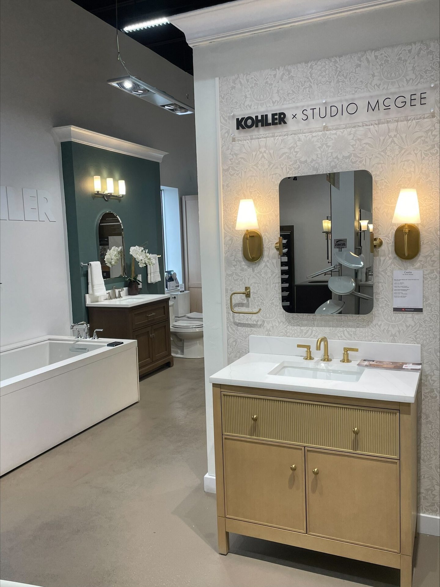 Modern bathroom showroom with two vanity setups, a tub, and Kohler x Studio McGee branding.