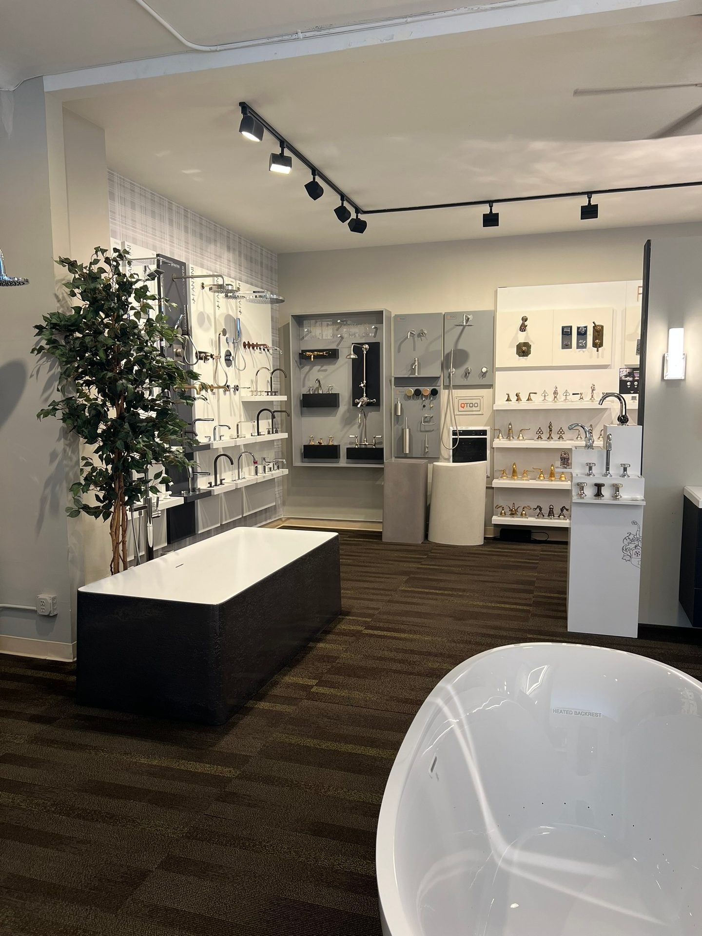 Modern bathroom showroom with bathtubs and wall-mounted faucet and shower displays.