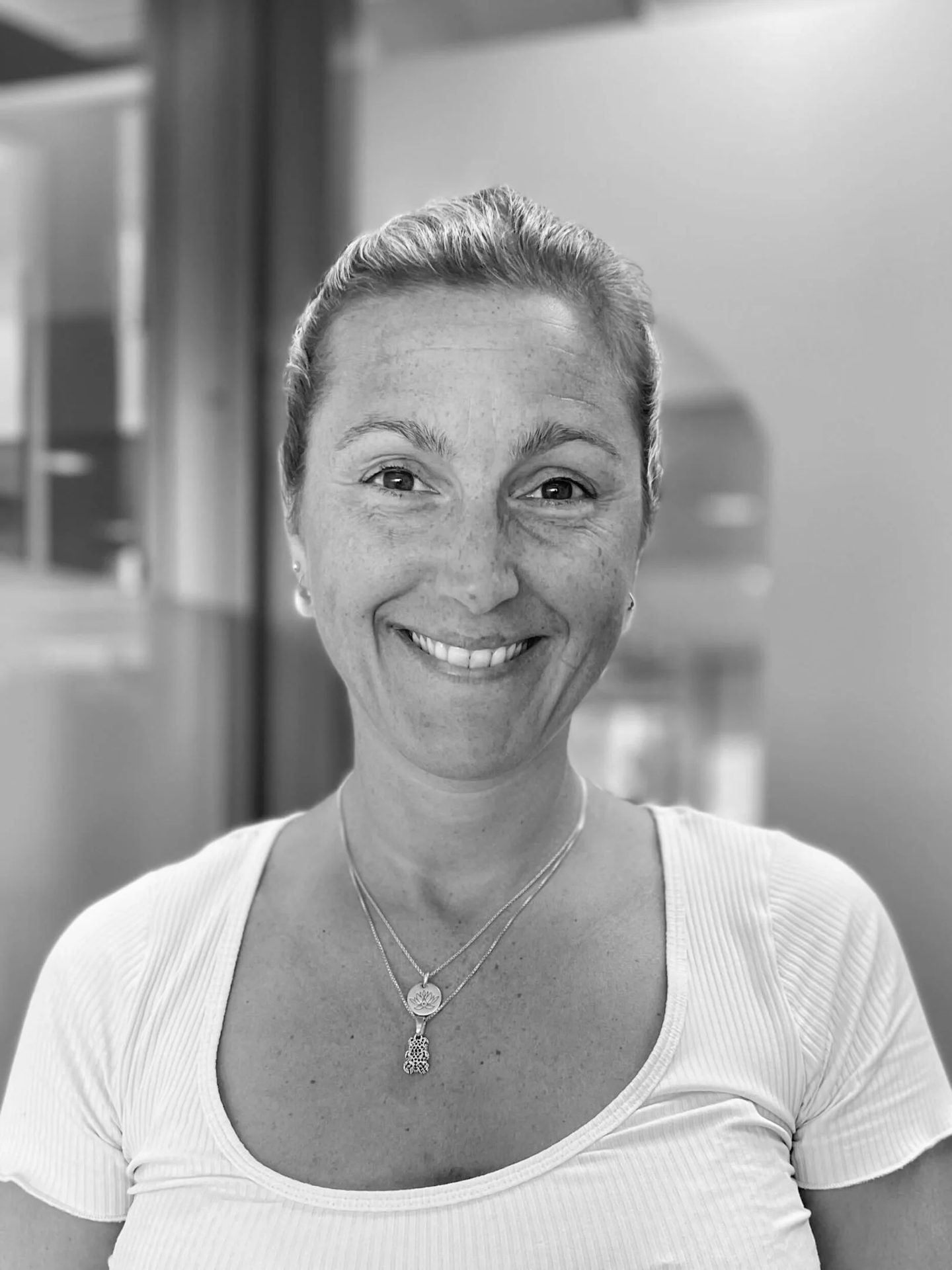 Black and white headshot of a smiling woman with freckles.