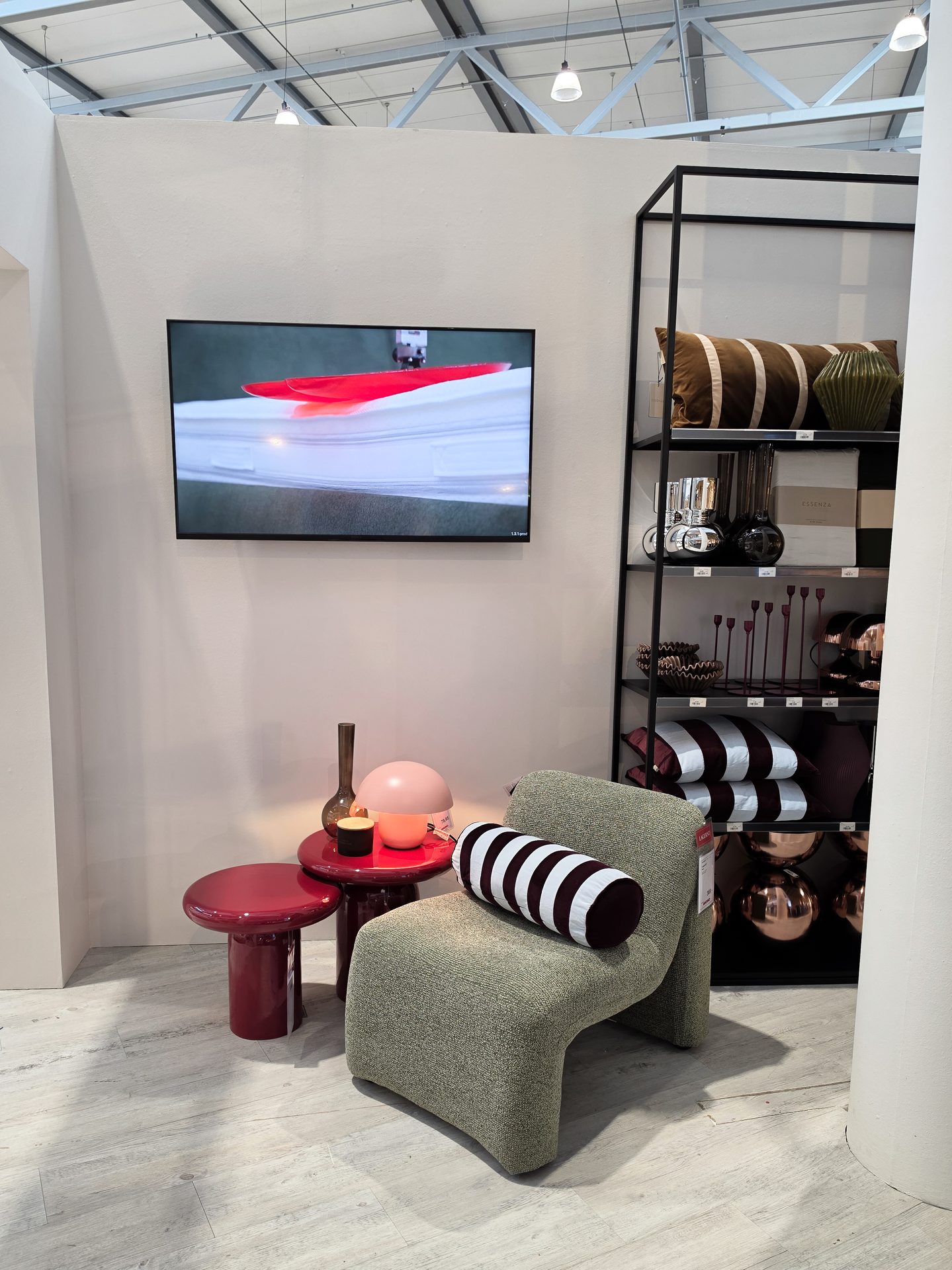 Modern living room with a green armchair, red tables, a TV, and a black shelving unit.