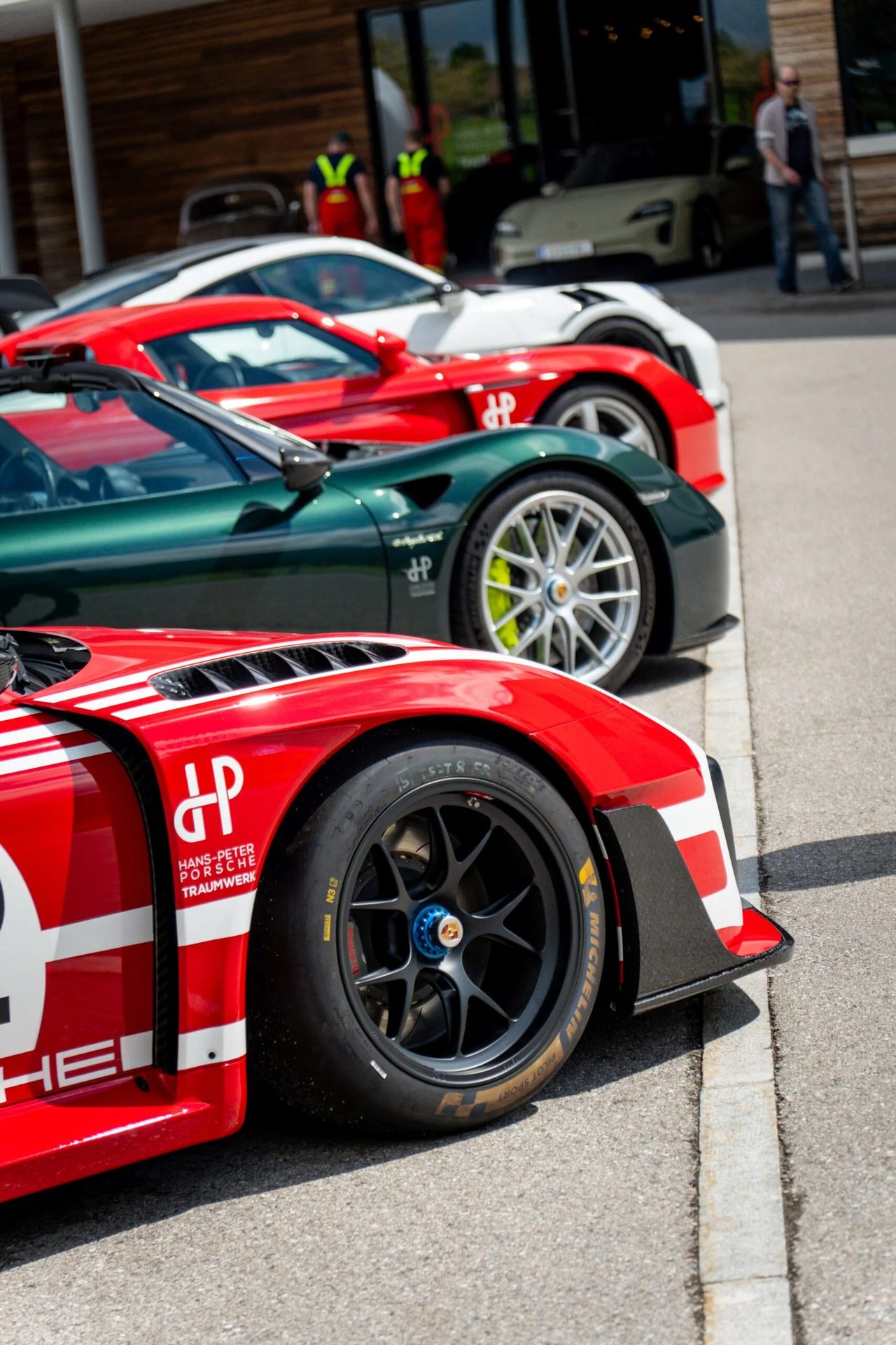A row of high-performance sports cars, including red, green, and white models, parked outdoors.