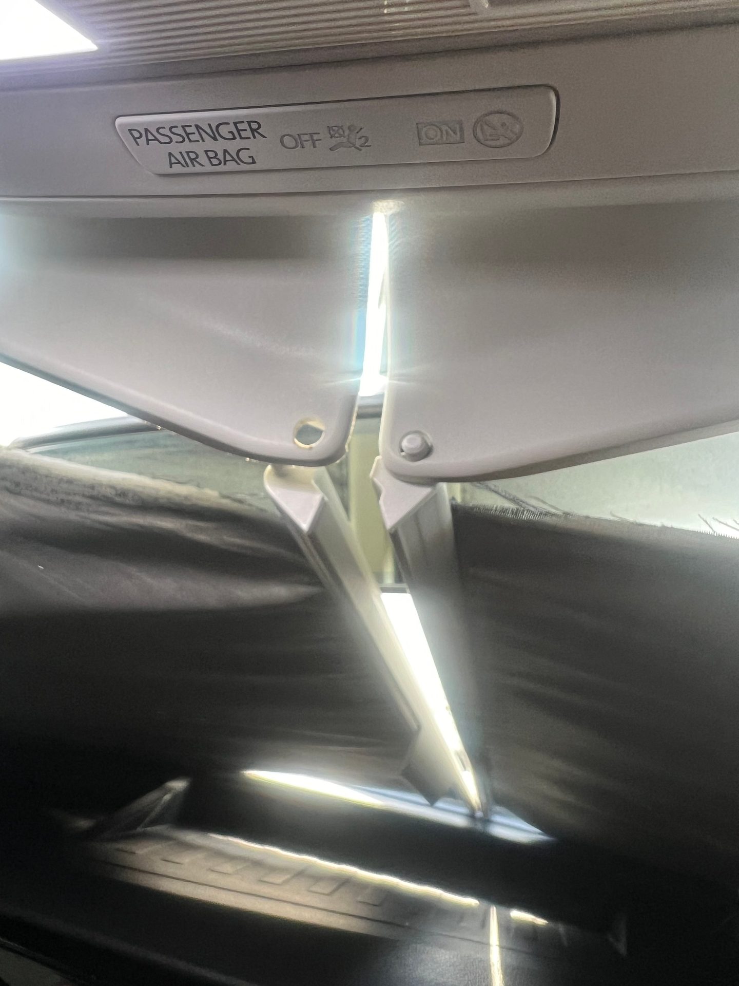 Car interior showing a "PASSENGER AIR BAG OFF ON" indicator, with sun visors and bright light.