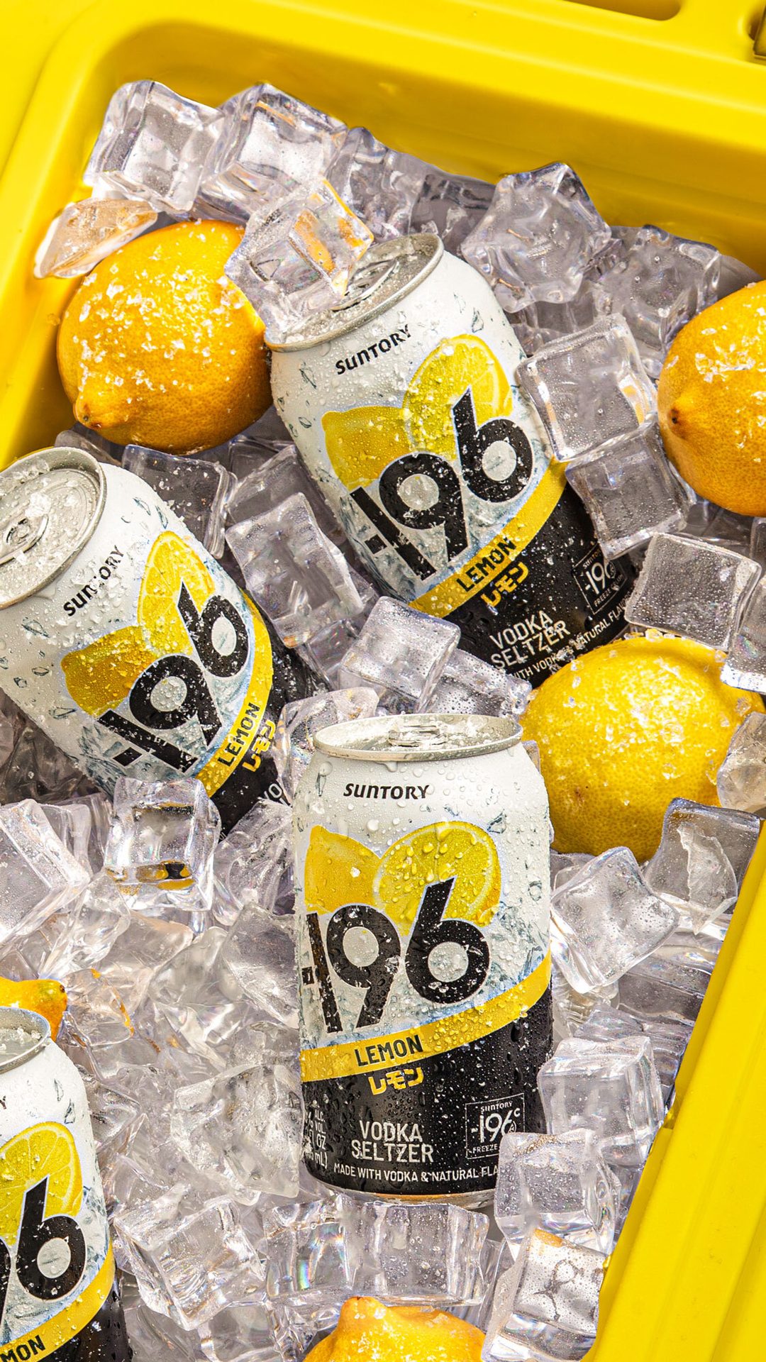 Cans of Suntory 196 Lemon Vodka Seltzer chilling in ice with fresh lemons in a yellow cooler.