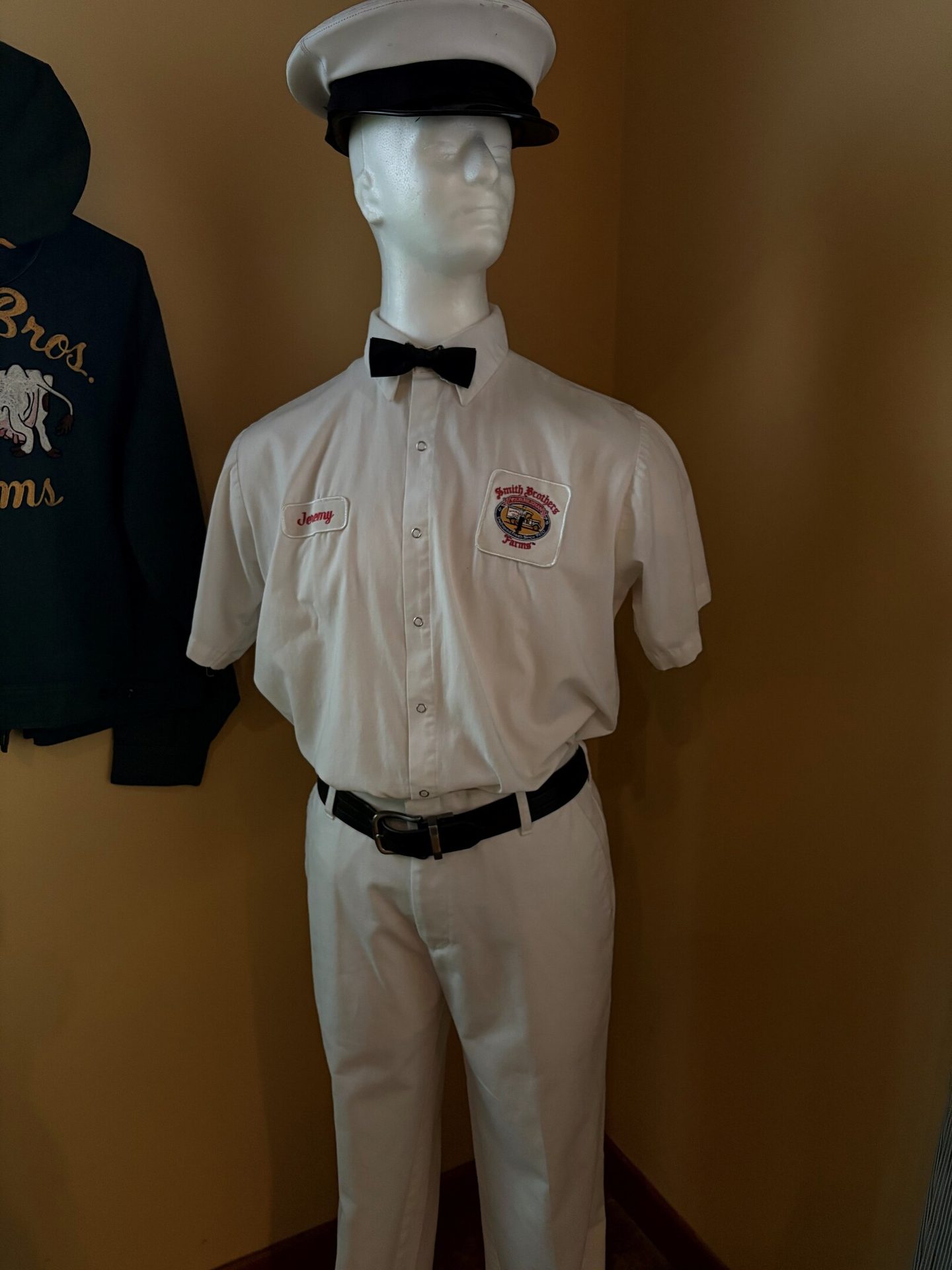 Mannequin in a white Smith Brothers Farms milk delivery uniform with cap, bow tie, and 'Jeremy' tag.