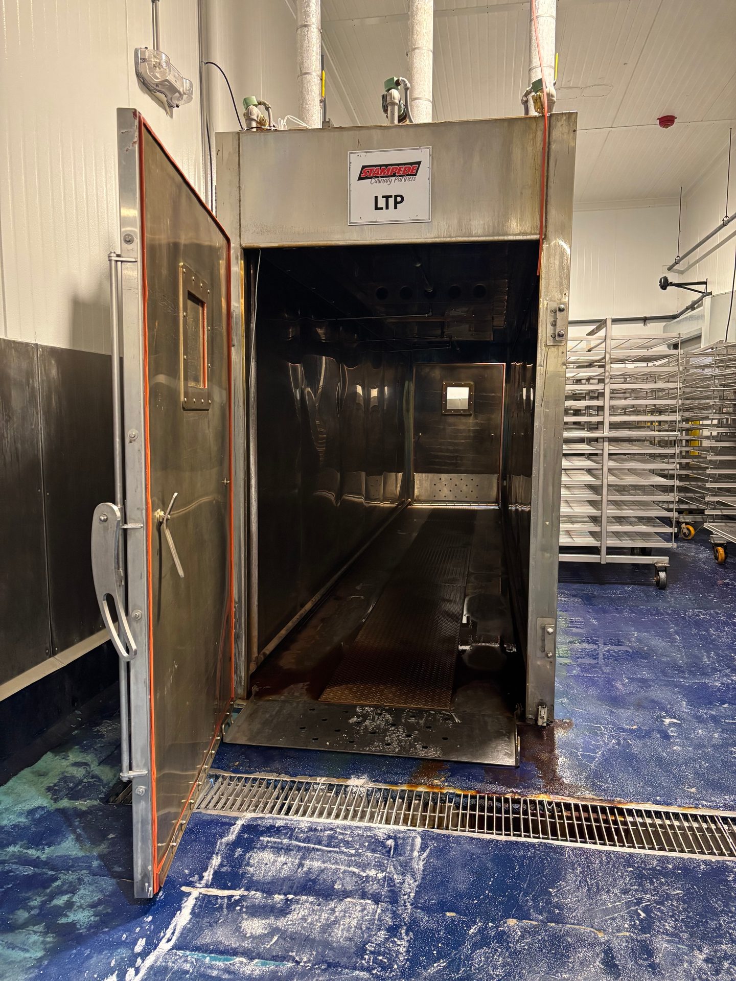 Open industrial stainless steel chamber, 'STAMPEDE Culinary Partners LTP' label, blue floor.