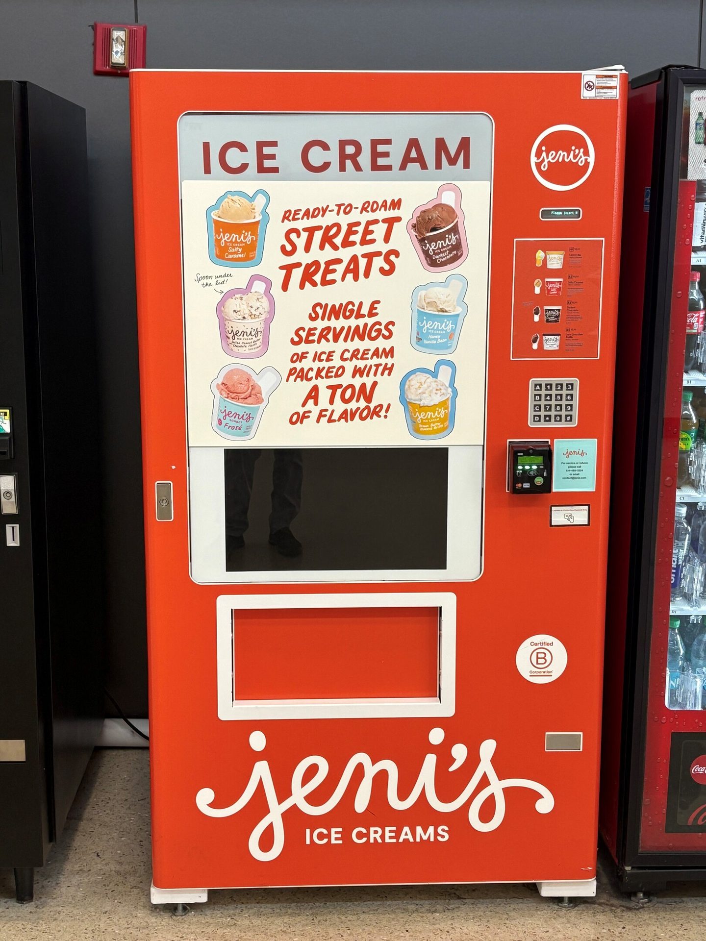 An orange Jeni's Ice Cream vending machine, displaying flavors and payment options.