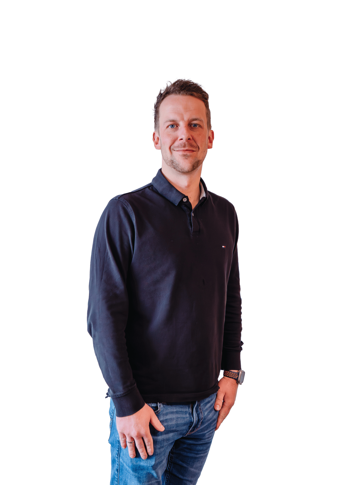 Smiling man in dark polo shirt and jeans on green background.