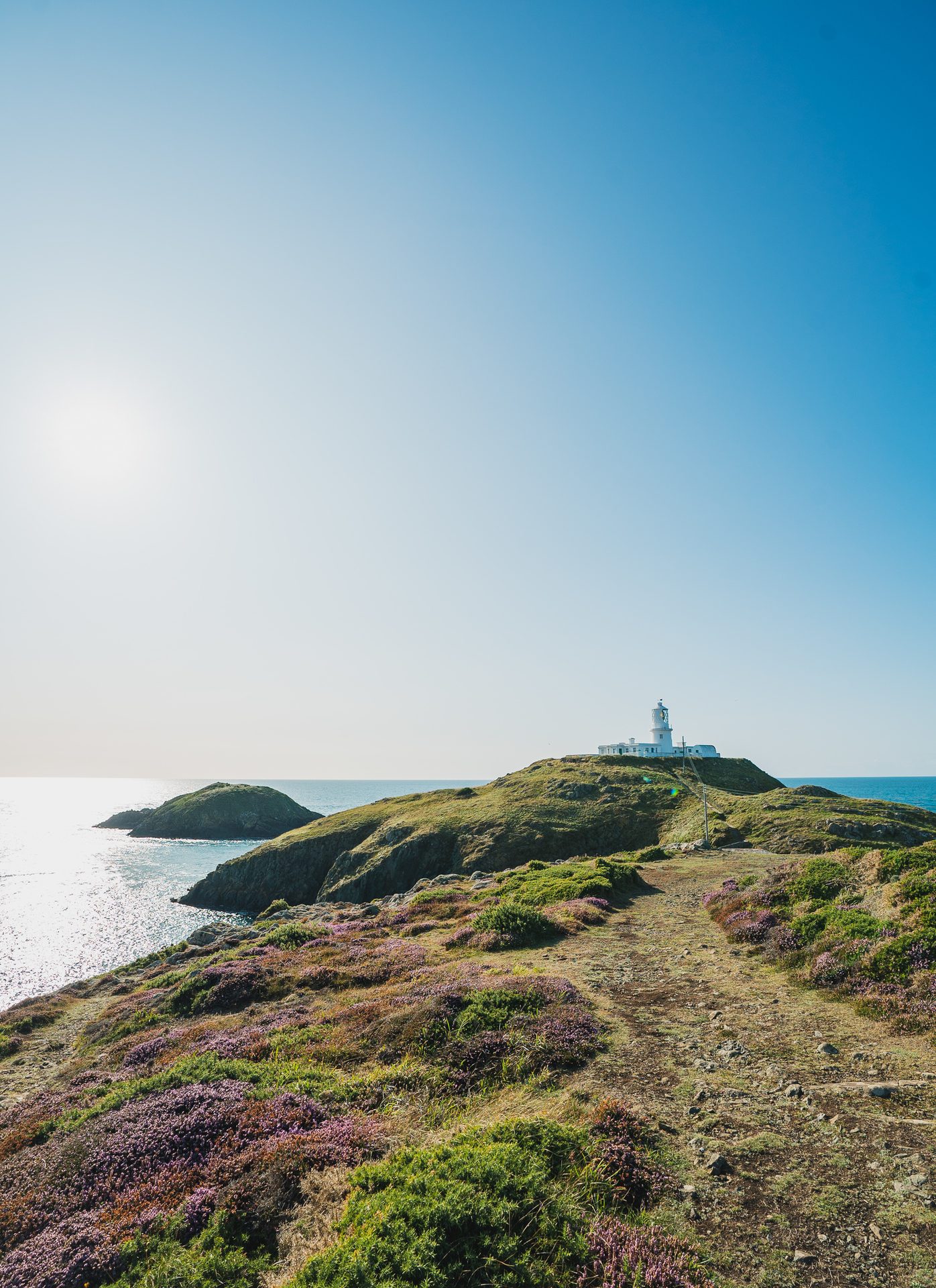 Coastal and oceanic landforms, Natural landscape, Water, Sky, Plant, Lighthouse, Terrain, Horizon, Grass