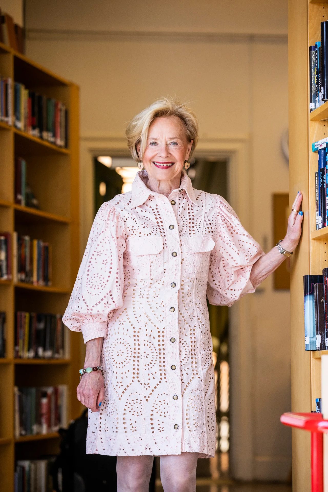 Dress shirt, Fashion design, Smile, Bookcase, Shelf, Textile, Sleeve, Shelving