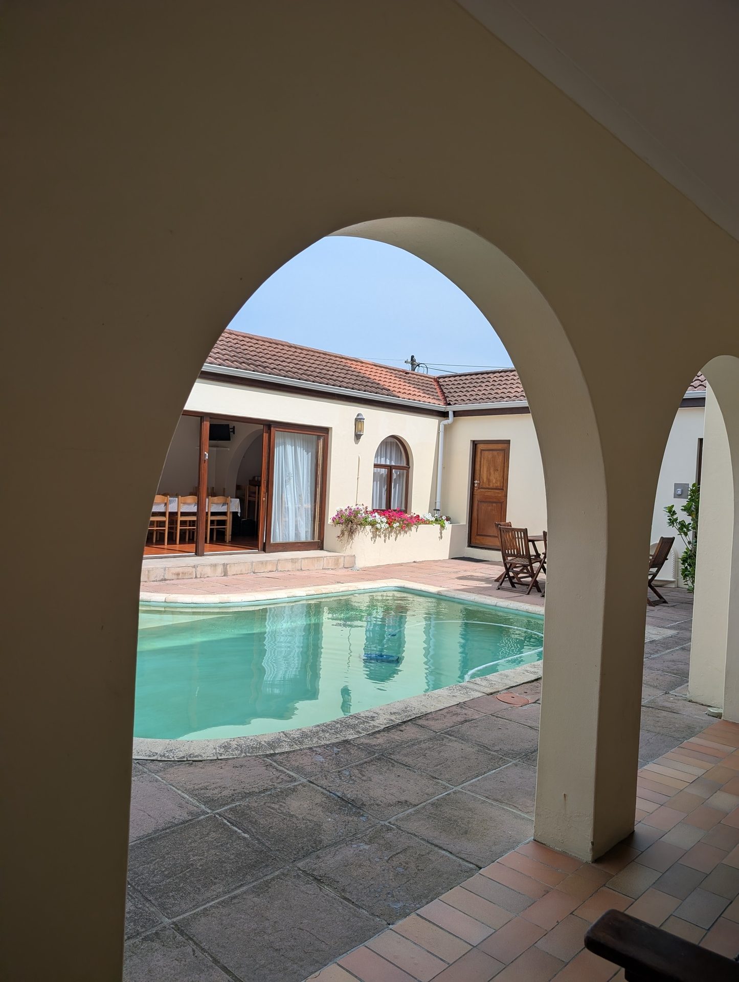 A inviting courtyard with a swimming pool and buildings, framed by architectural arches.