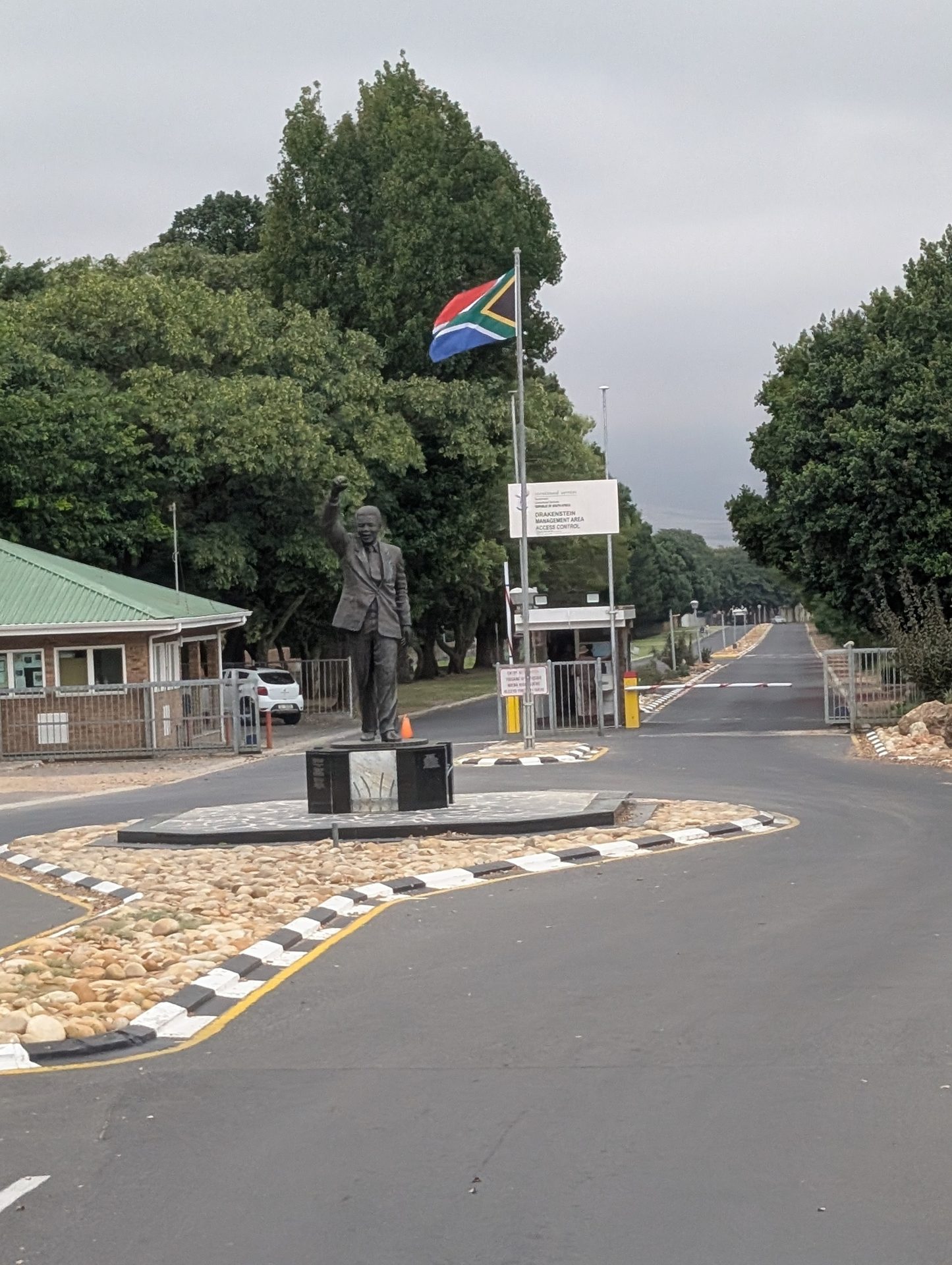 A statue of Nelson Mandela with a South African flag and an access control gate at Drakenstein.