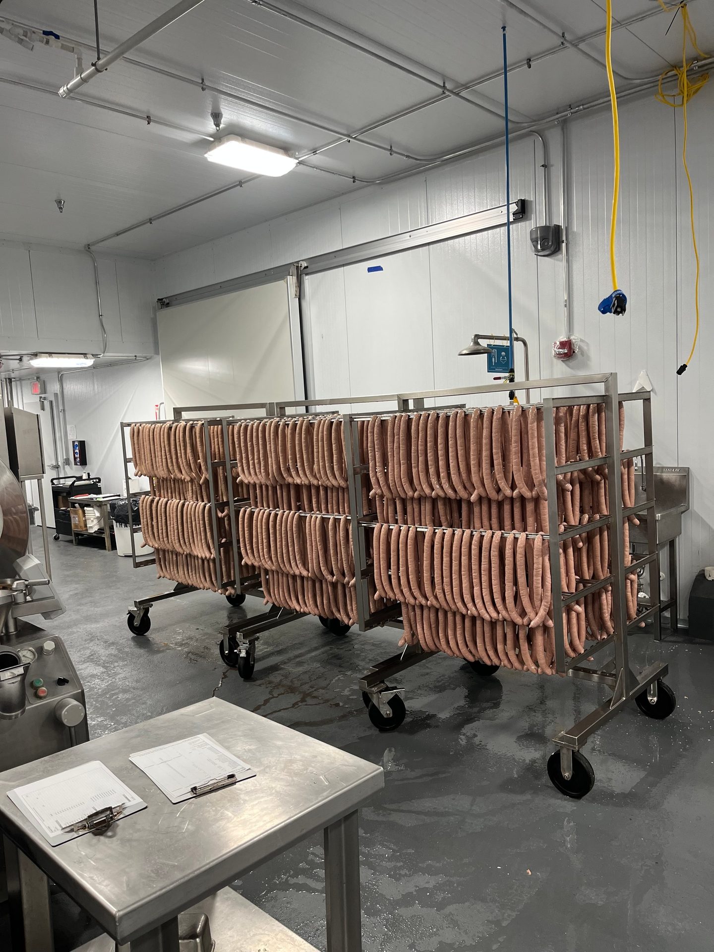 Raw sausages hanging on racks in a food processing plant.