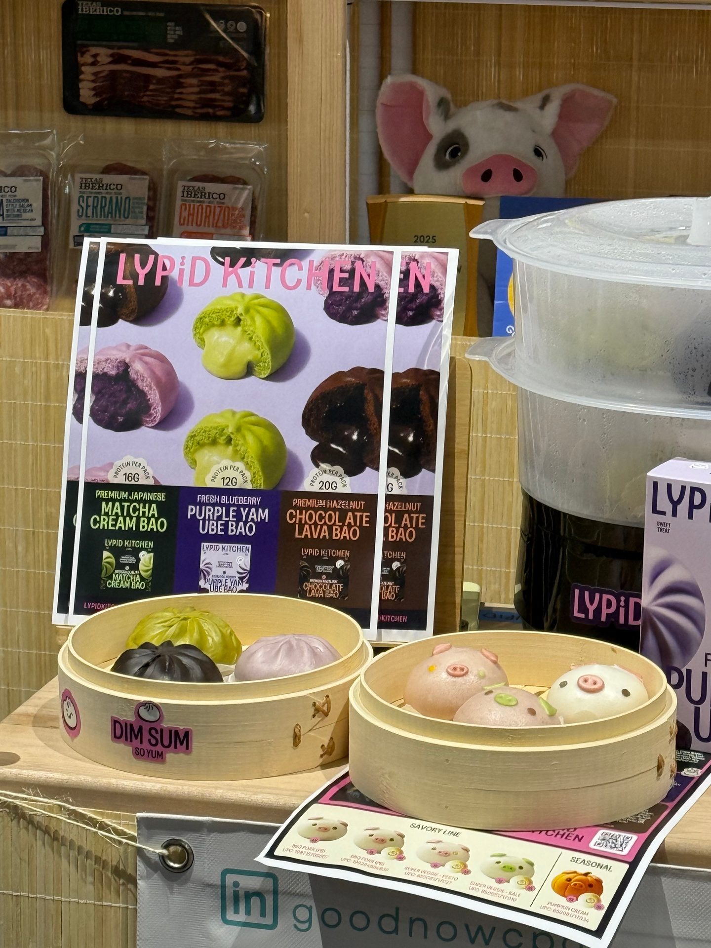 Colorful Lypid Kitchen dim sum bao buns in bamboo steamers displayed with a branded poster and products.