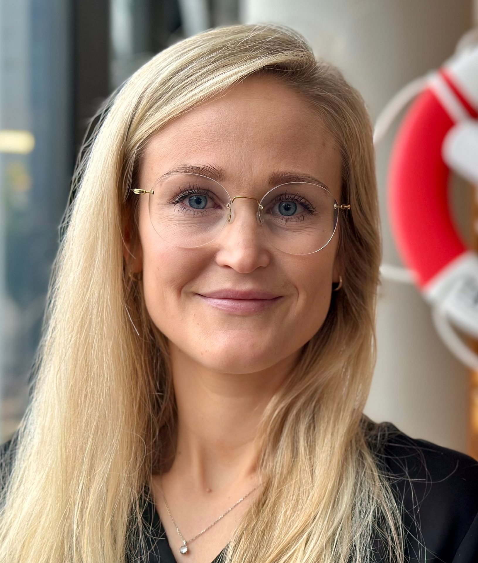 A smiling woman with blonde hair and glasses looking at the camera.