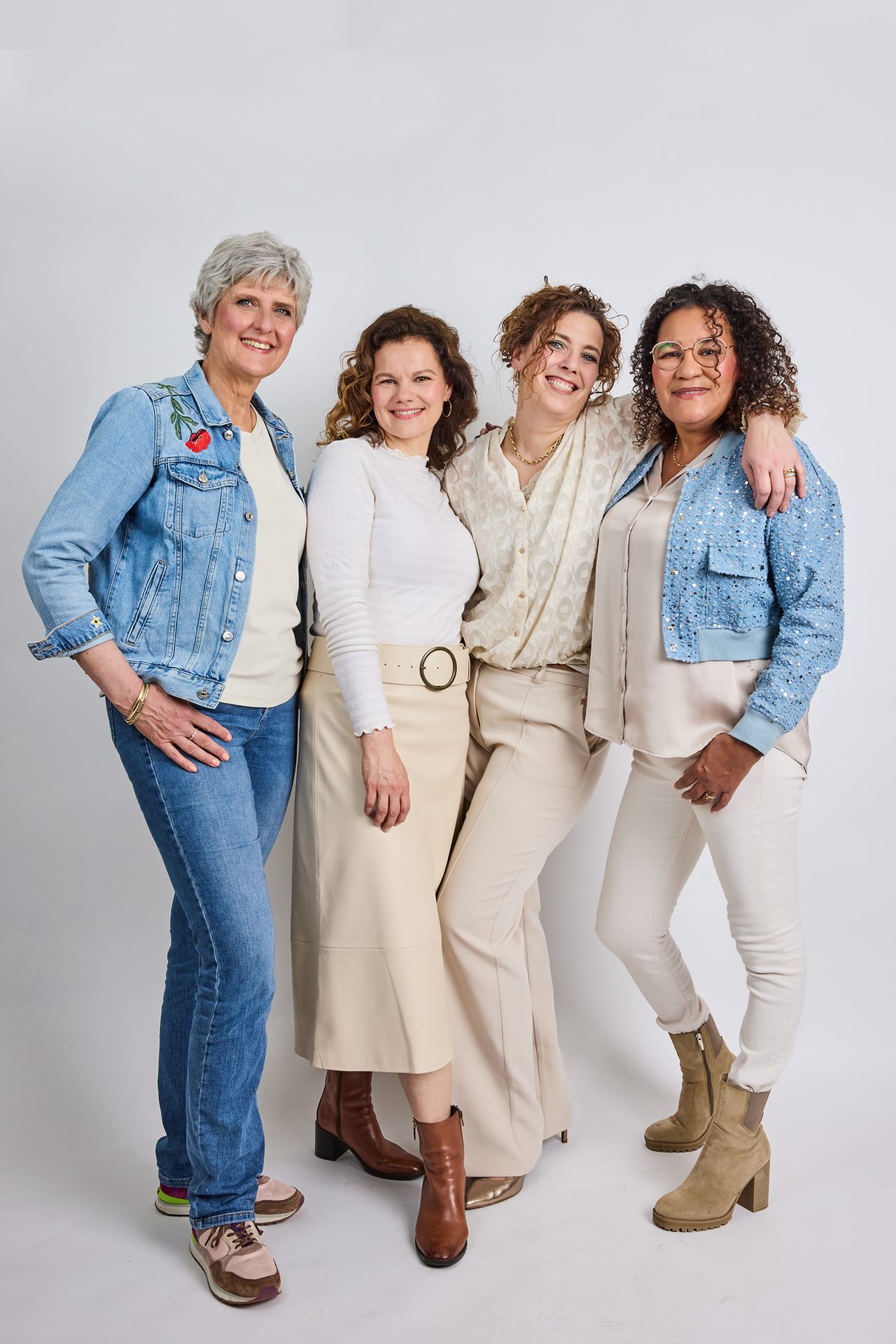 Four diverse women of varying ages smiling and standing together.