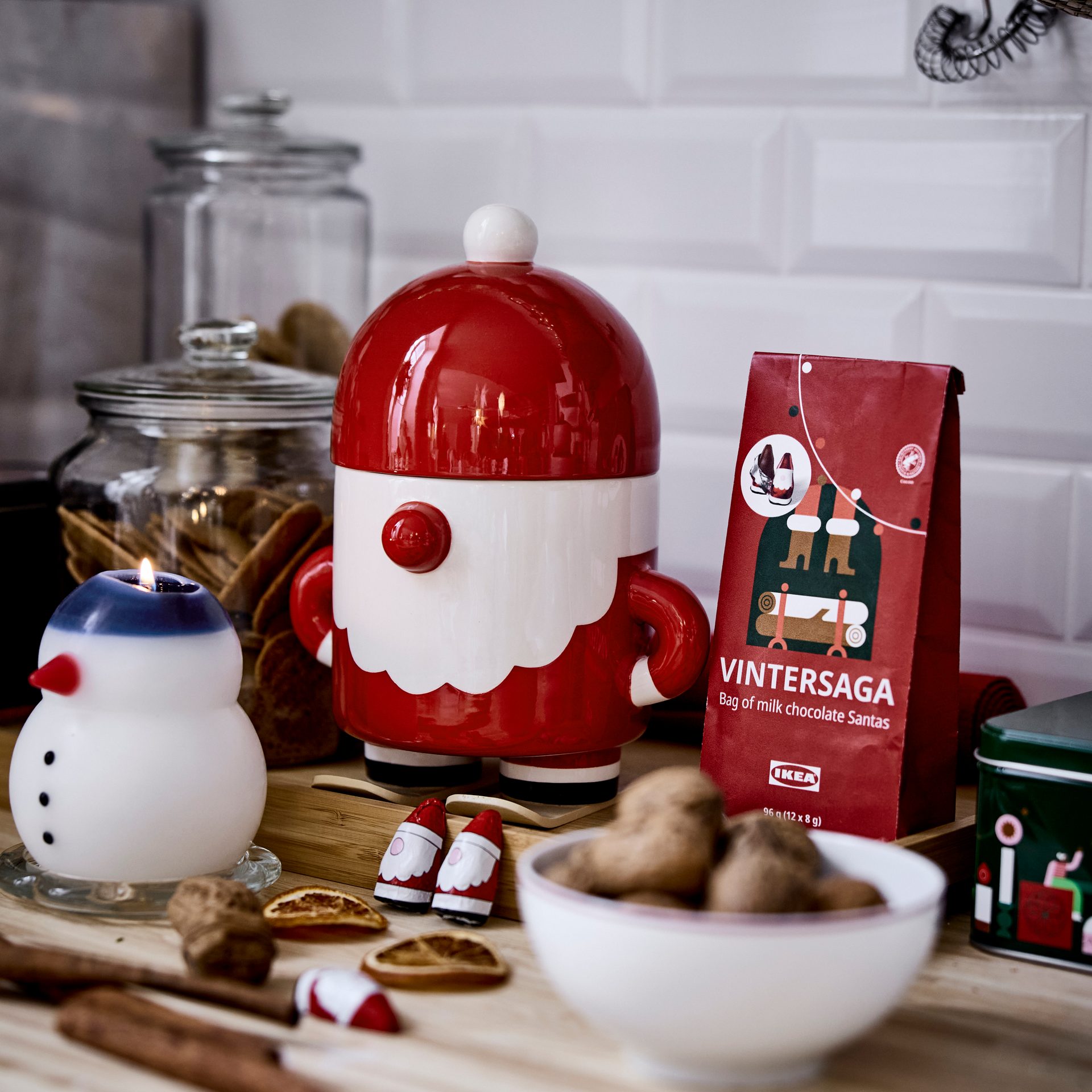 Festive kitchen counter with a Santa container, snowman candle, and various Christmas snacks.
