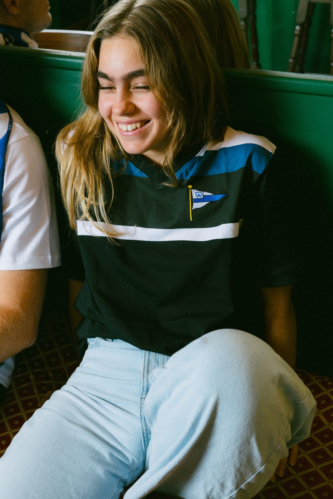 A smiling young woman with blonde hair, wearing a black, blue, and white striped shirt.