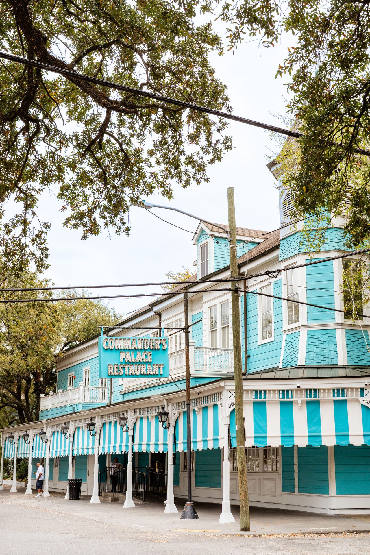 The iconic Commander's Palace Restaurant in New Orleans, with its striking turquoise facade and striped awnings.