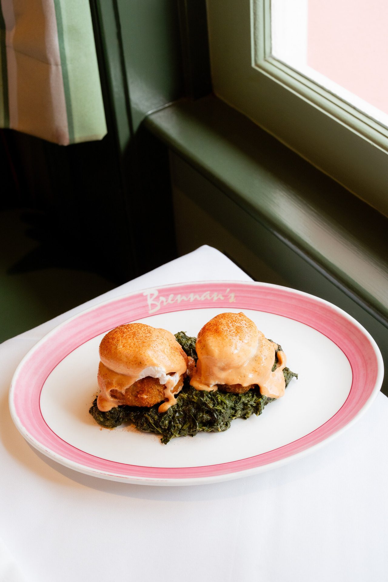 Two eggs Sardou, poached eggs on fried artichoke hearts with creamed spinach and hollandaise, on a plate.