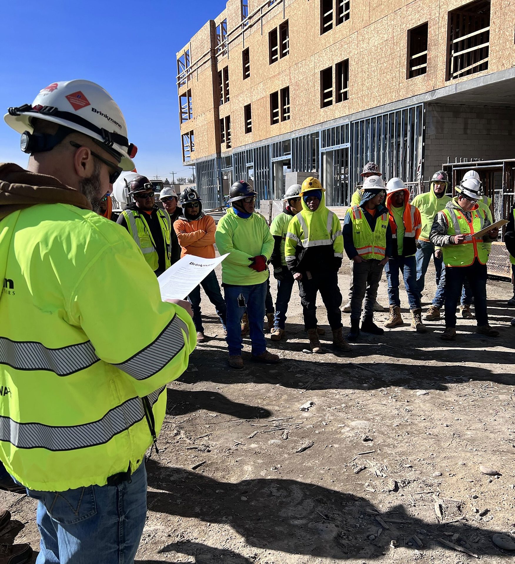 Hard hat, High-visibility clothing, Road surface, Workwear, Helmet, Building, Window, Tradesman, Infrastructure, Asphalt