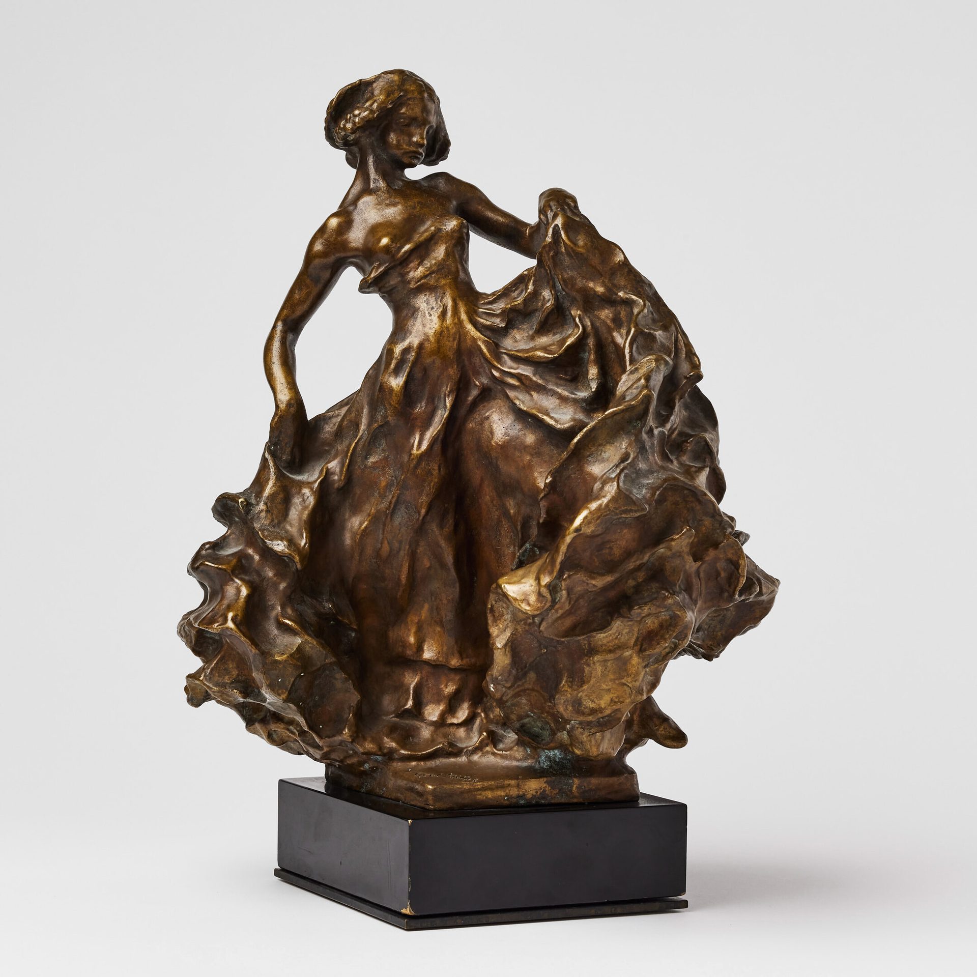 A detailed bronze sculpture of a woman in a flowing, ruffled dress, captured in a dynamic dance pose.