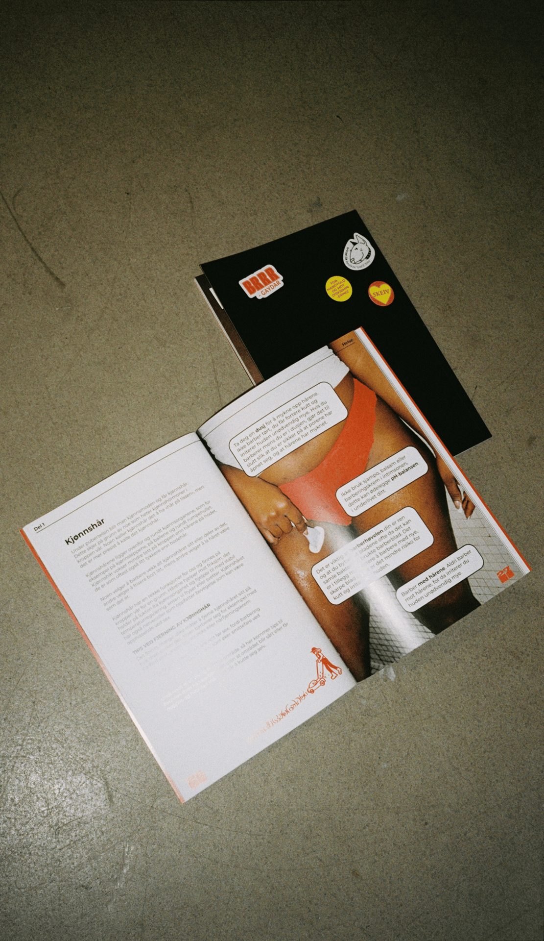An open magazine with an article about body hair and a woman's lower body on a concrete floor.