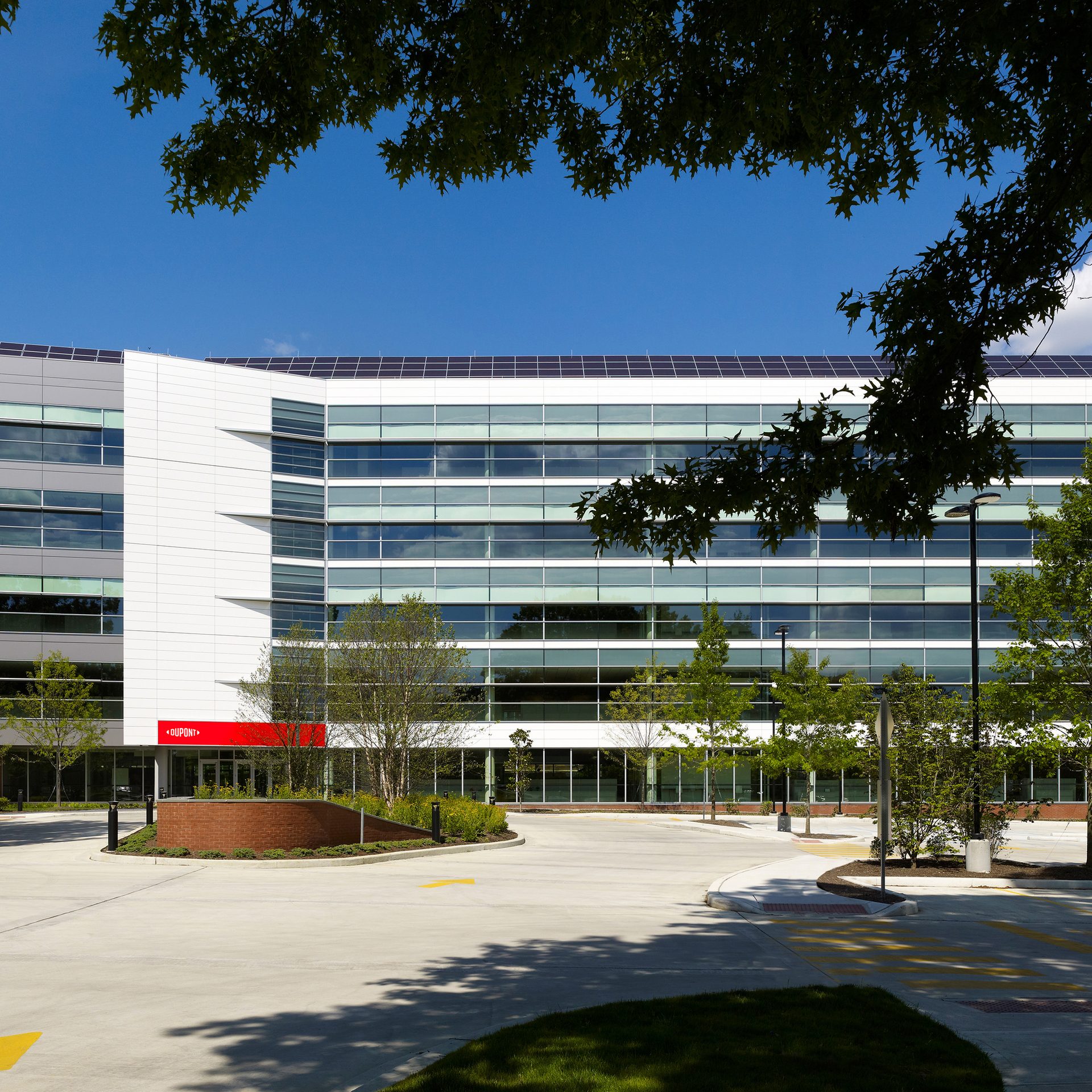 Modern office building with solar panels, a red "DUPONT" sign, and curved driveway.
