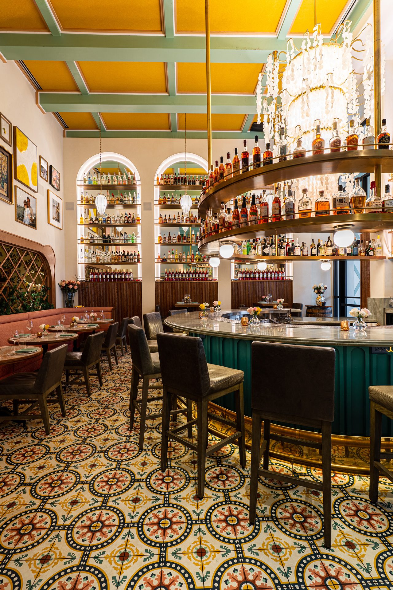 Lively bar with circular bottle display, colorful tiled floor, and yellow and green ceiling.