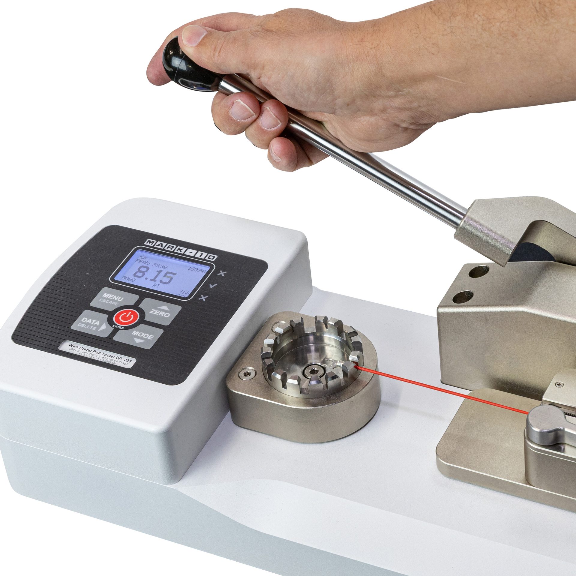 Hand operates Mark-10 wire crimp pull tester; red wire is being tested, display reads 8.15.